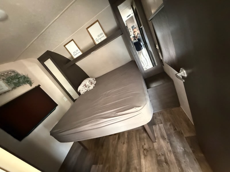 Compact RV rental bedroom featuring a comfortable bed, wood-look floor, and charming wall decor for your travels.. Forest River Salem 2019