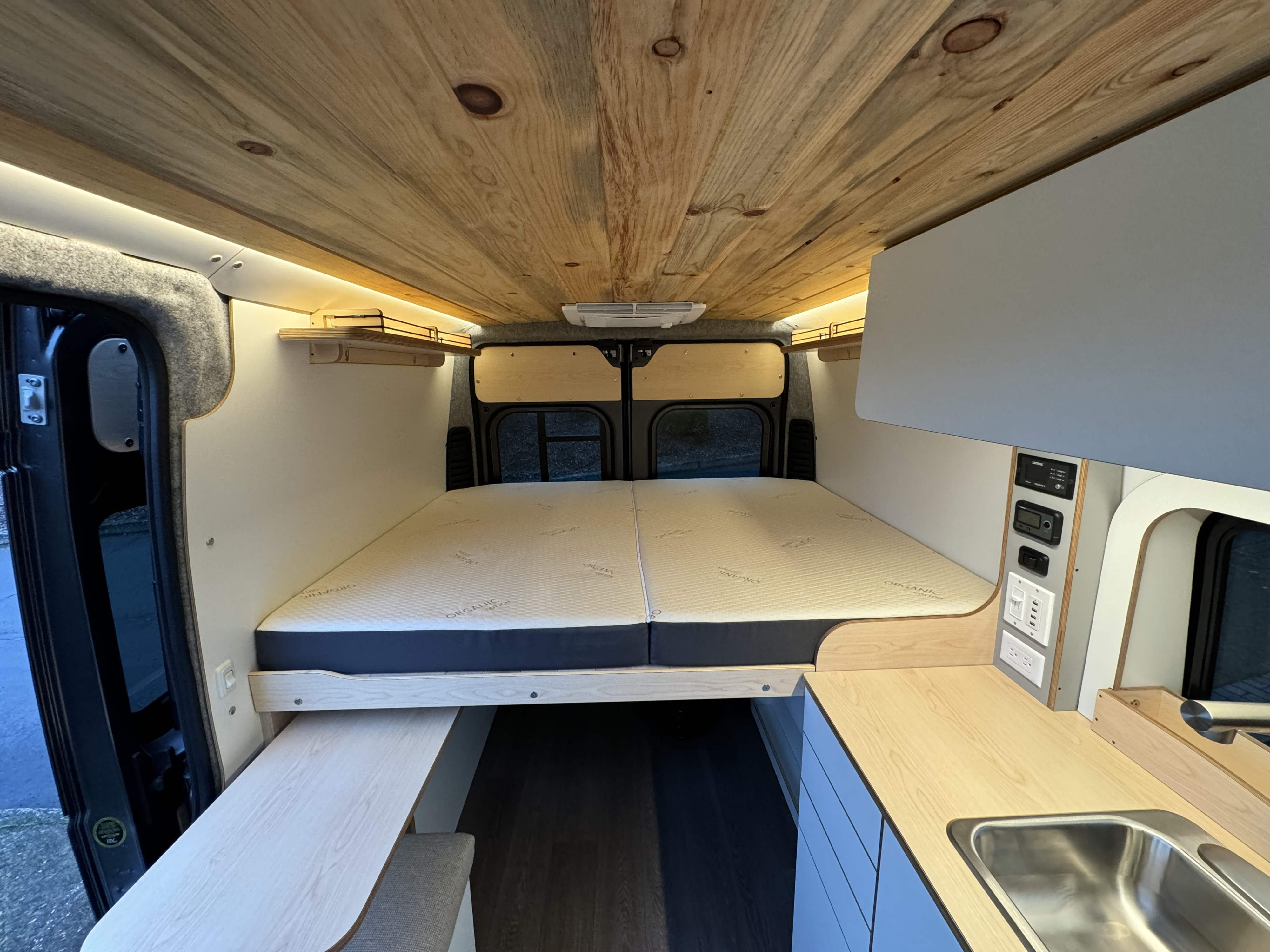 Step inside this bright RV rental camper van, featuring a bed, wood ceiling, kitchenette, and control panel.. Dave & Matt Vans Dave & Matt Vans Class B 2024