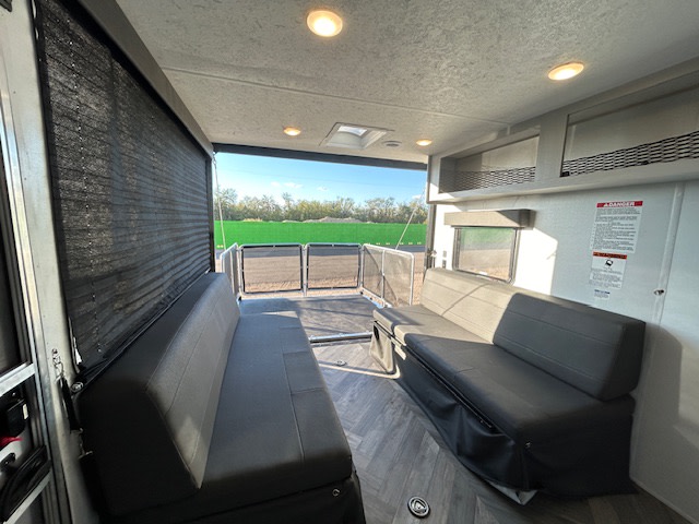 RV rental: Interior of a toy hauler with dual sofas, open ramp/deck, and scenic outdoor view.. Forest River Wildwood 2021