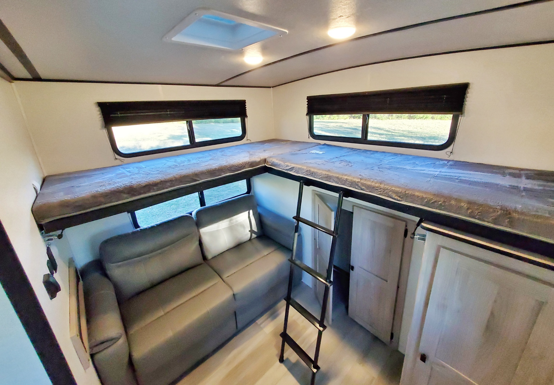 RV rental interior featuring an L-shaped loft bed, ladder, and comfortable sofa, maximizing sleeping and living space.. Coachmen Northern Spirit 2024