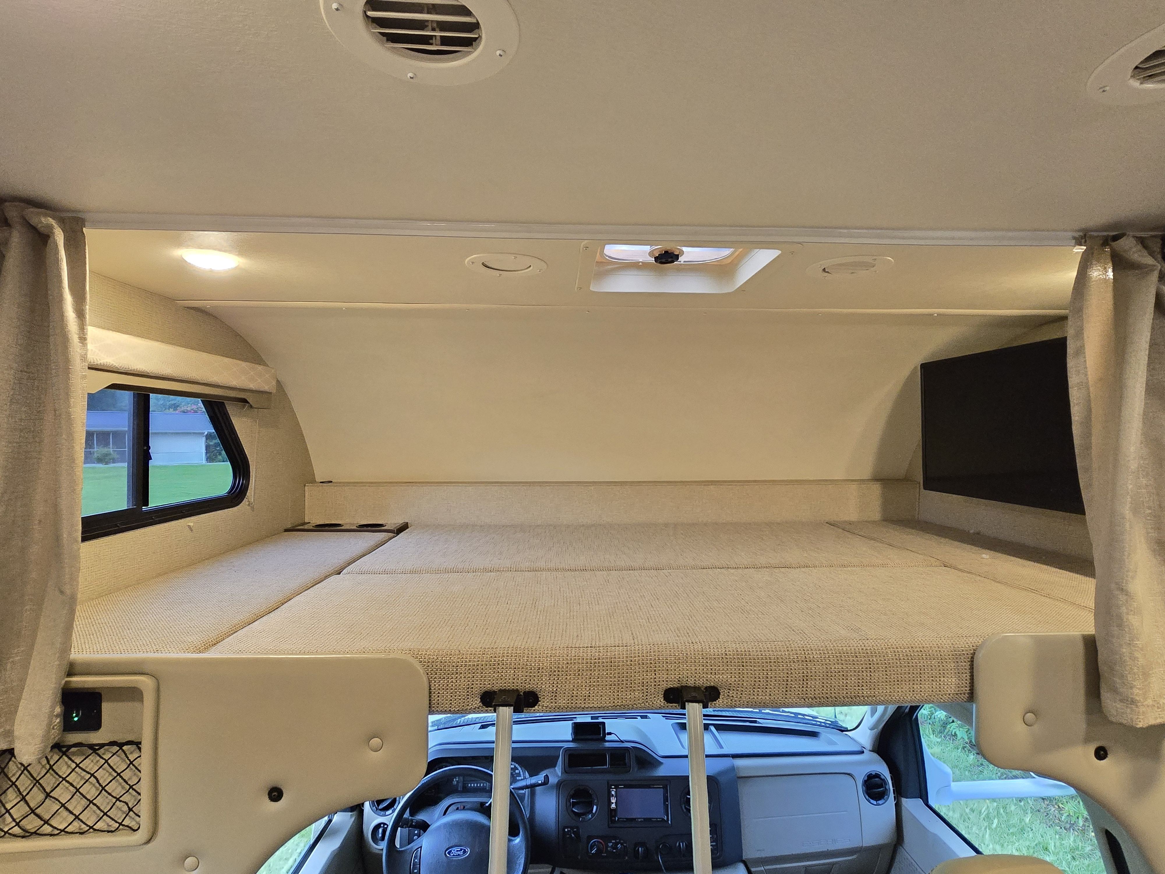 Spacious rv rental cab-over bunk bed setup with Ford dash below, ideal for comfortable travels.. Thor Freedom Elite 2019