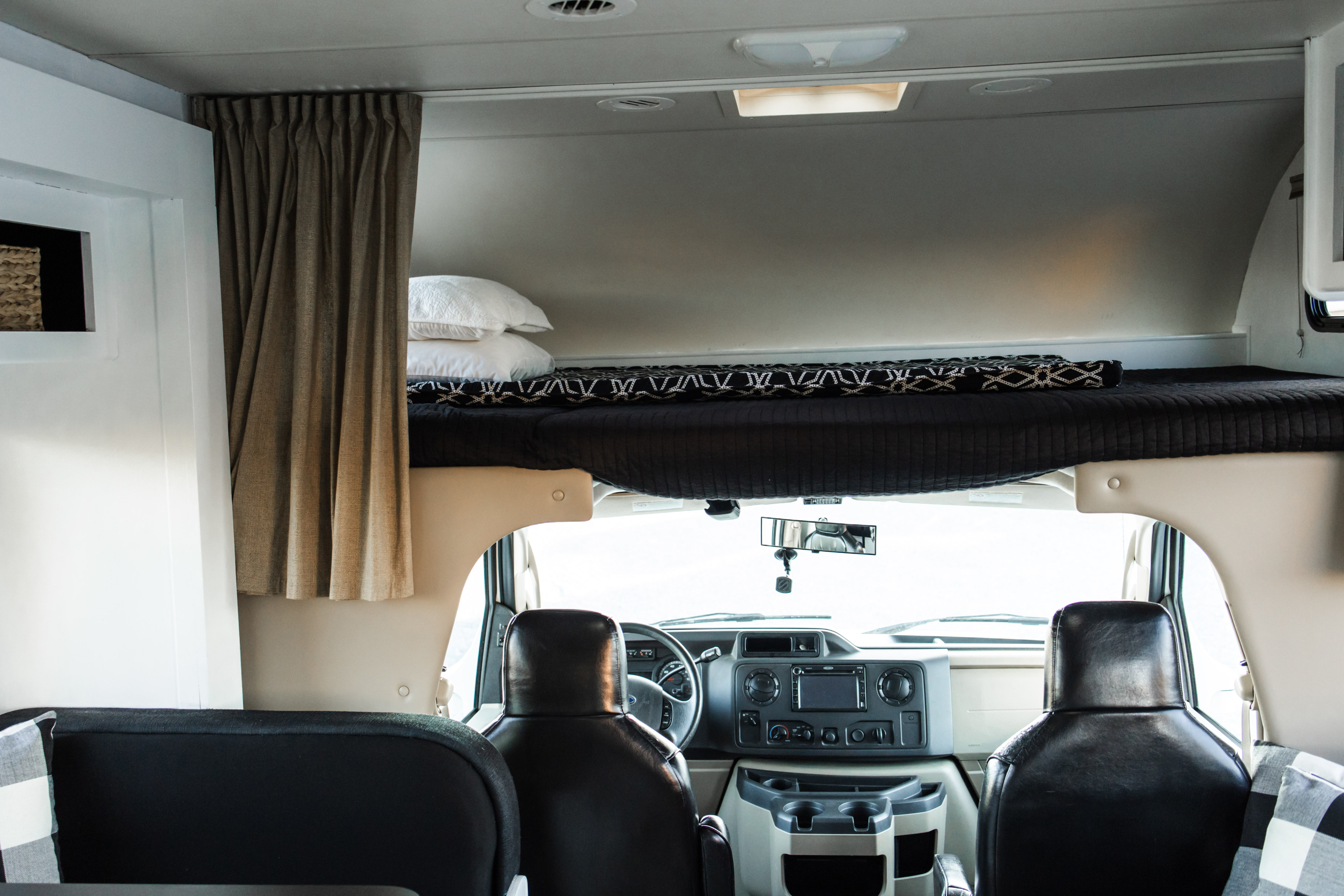 RV rental interior showing over-cab bunk bed, driver's area, and cabin seating from a rear perspective.. Four Winds Chateau 2011
