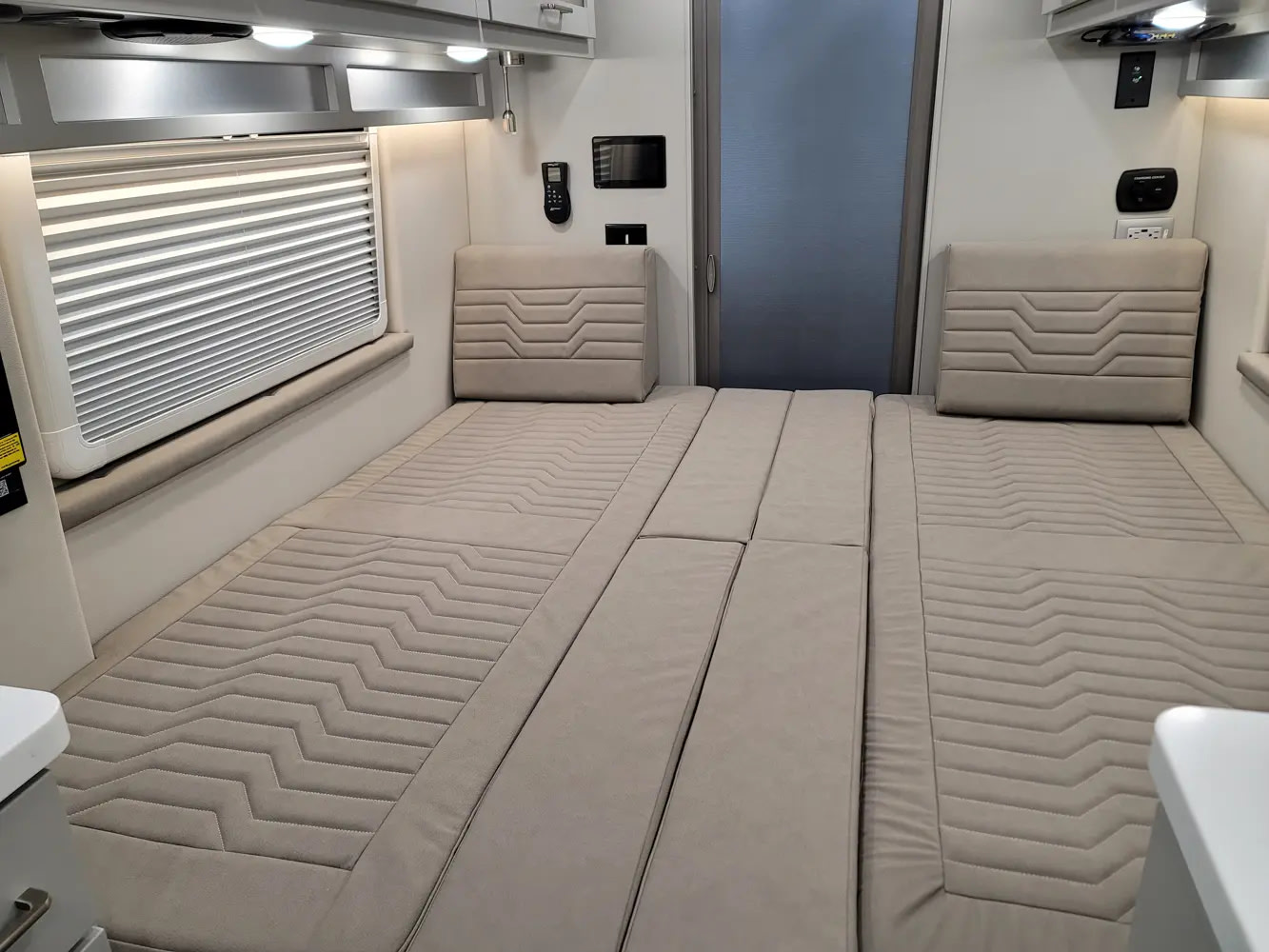 RV rental: A cozy, segmented bed with patterned beige cushions, integrated headrests, and window blinds for travel comfort.. Forest River Coachmen Nova 2026
