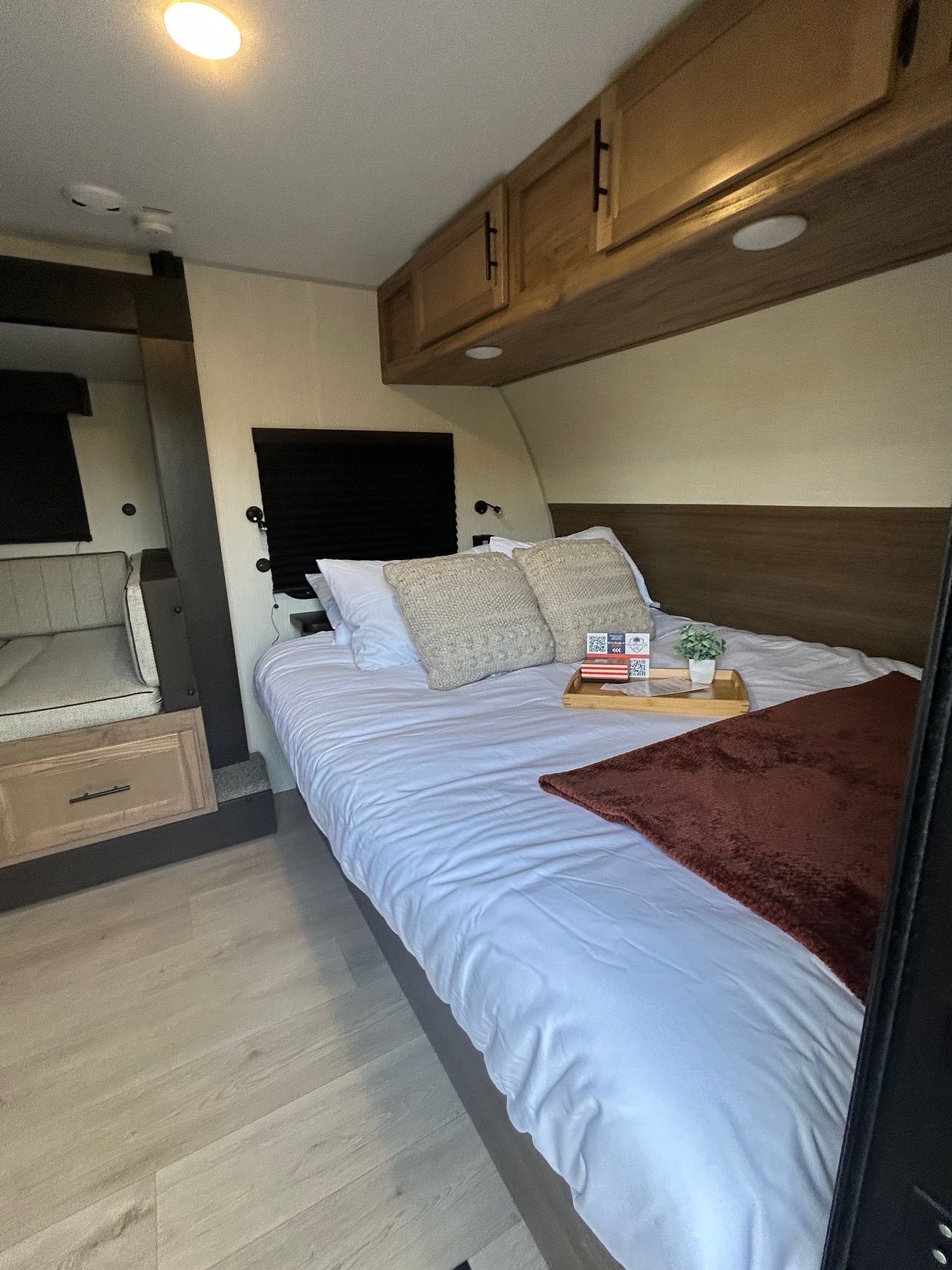Inside a modern **rv rental**, a comfy bedroom with a neatly made bed, decorative tray, and adjoining seating area.. Forest River RV Cherokee Wolf Pup Black Label 2025