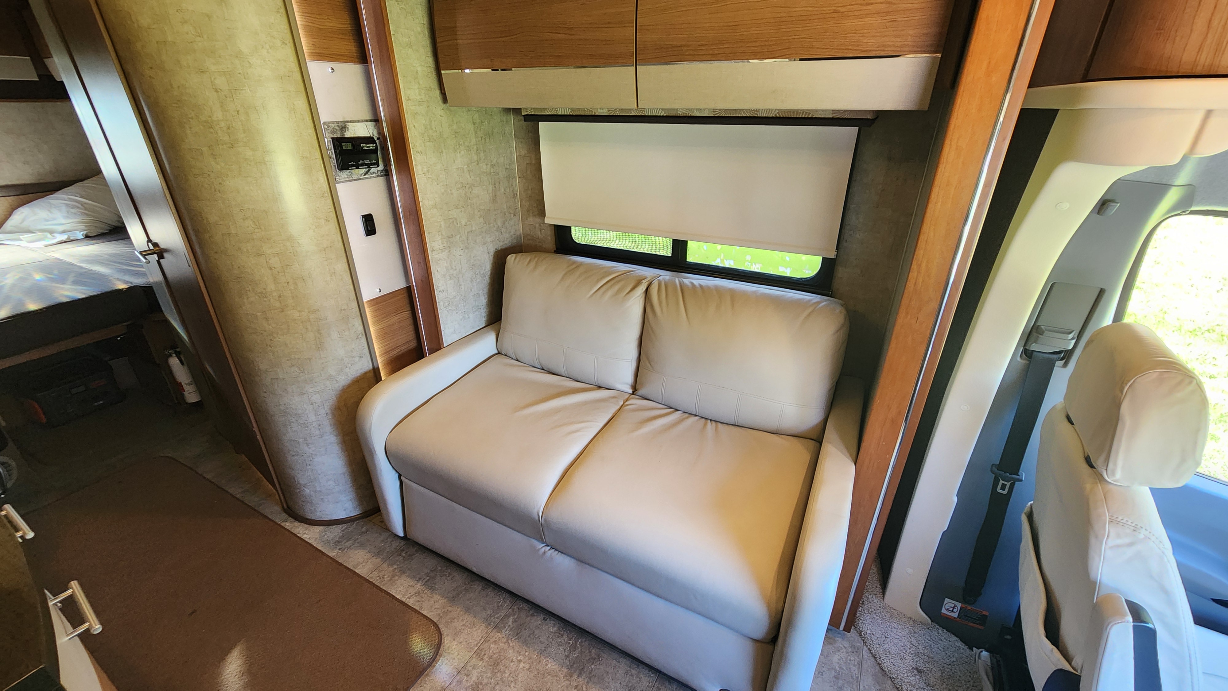 Cozy RV rental interior with cream sofa, window, and rear sleeping area for comfortable travel.. Winnebago View 2015