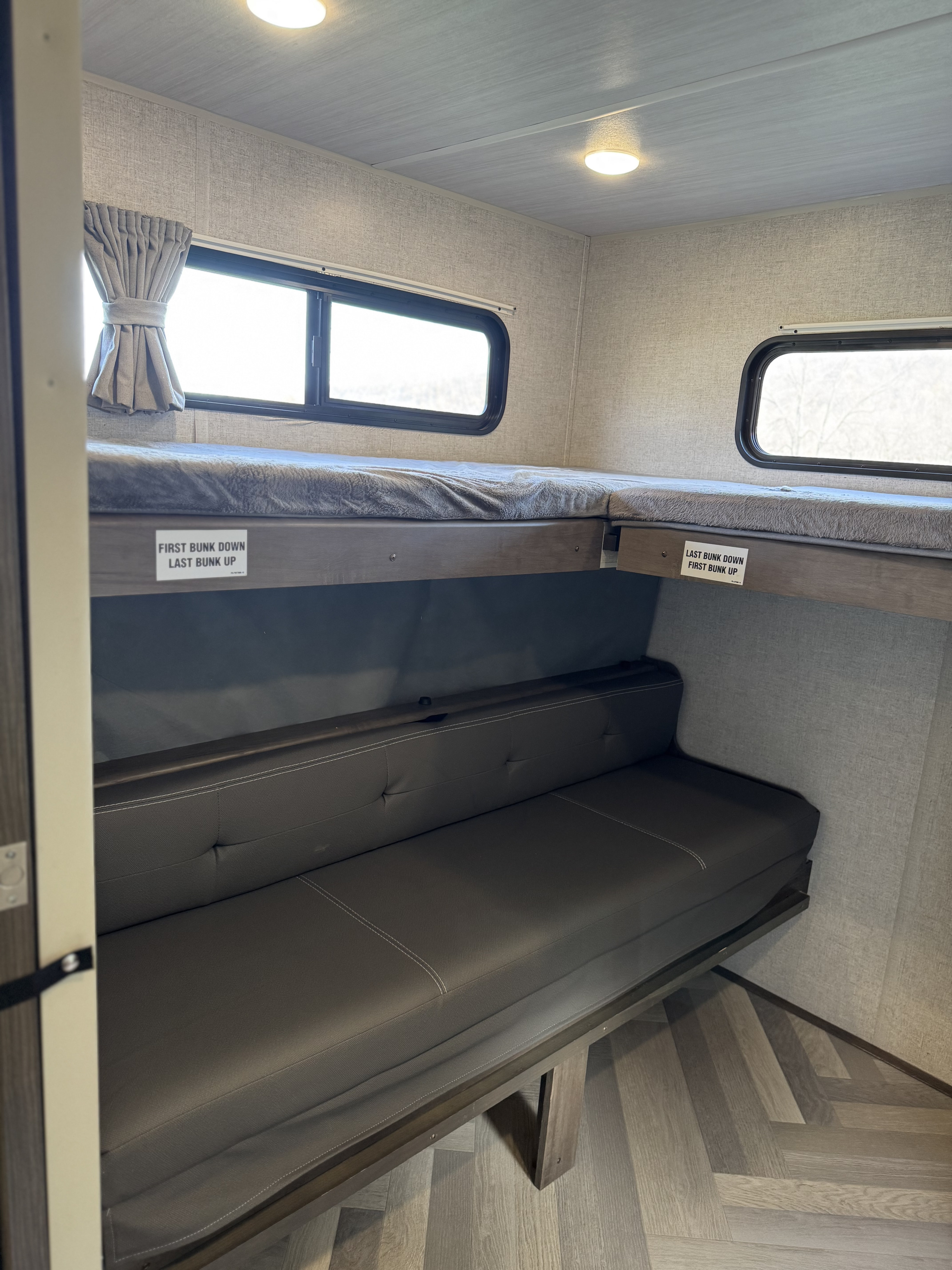 RV rental interior featuring flexible bunk beds above a sofa, ideal for sleeping and lounging in this compact space.. Forest River Wildwood 2021