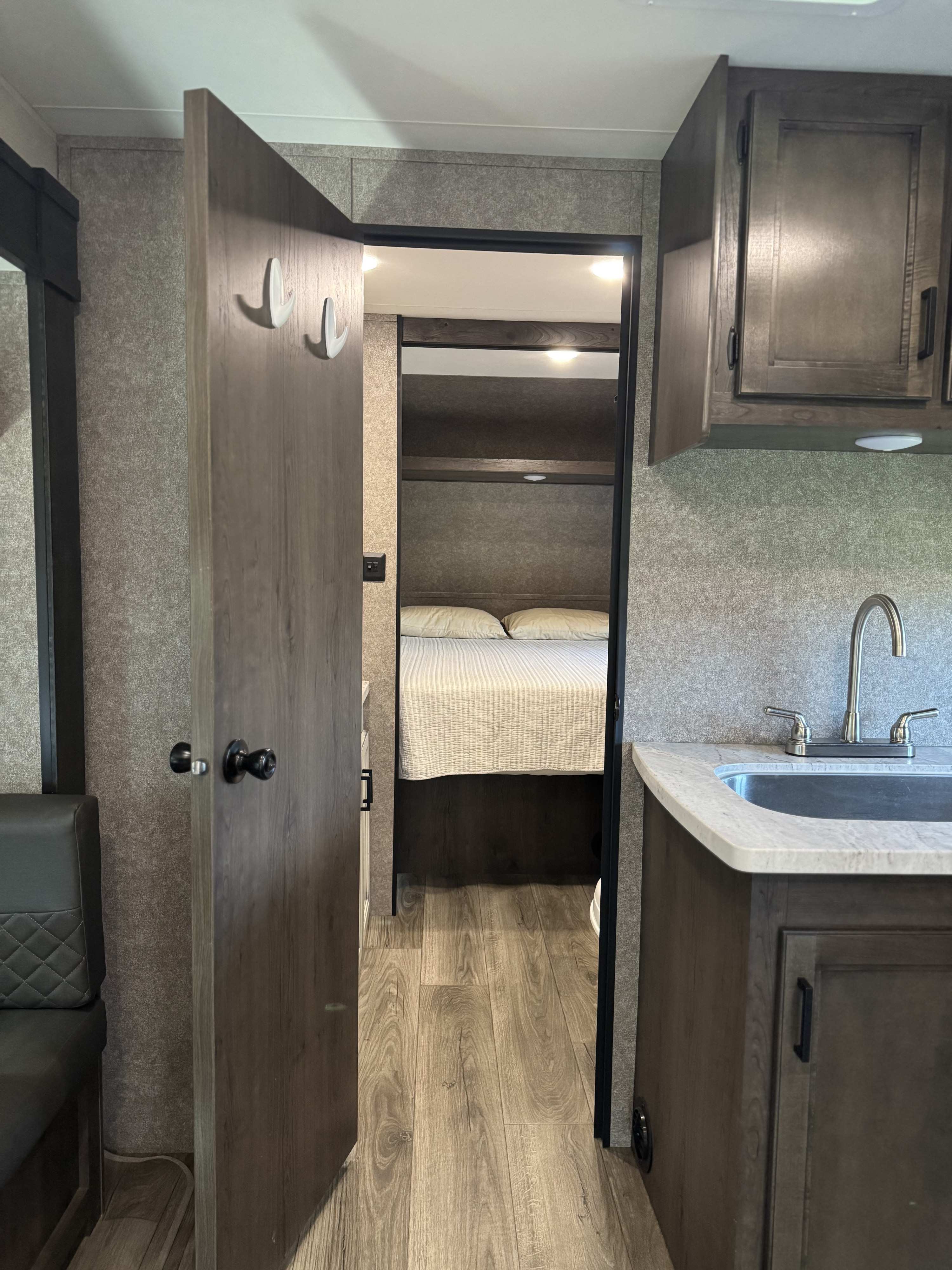 RV rental interior: a view of the hallway leading to a bedroom, with a kitchen sink and cabinets on the right.. Starcraft Autumn Ridge 2021