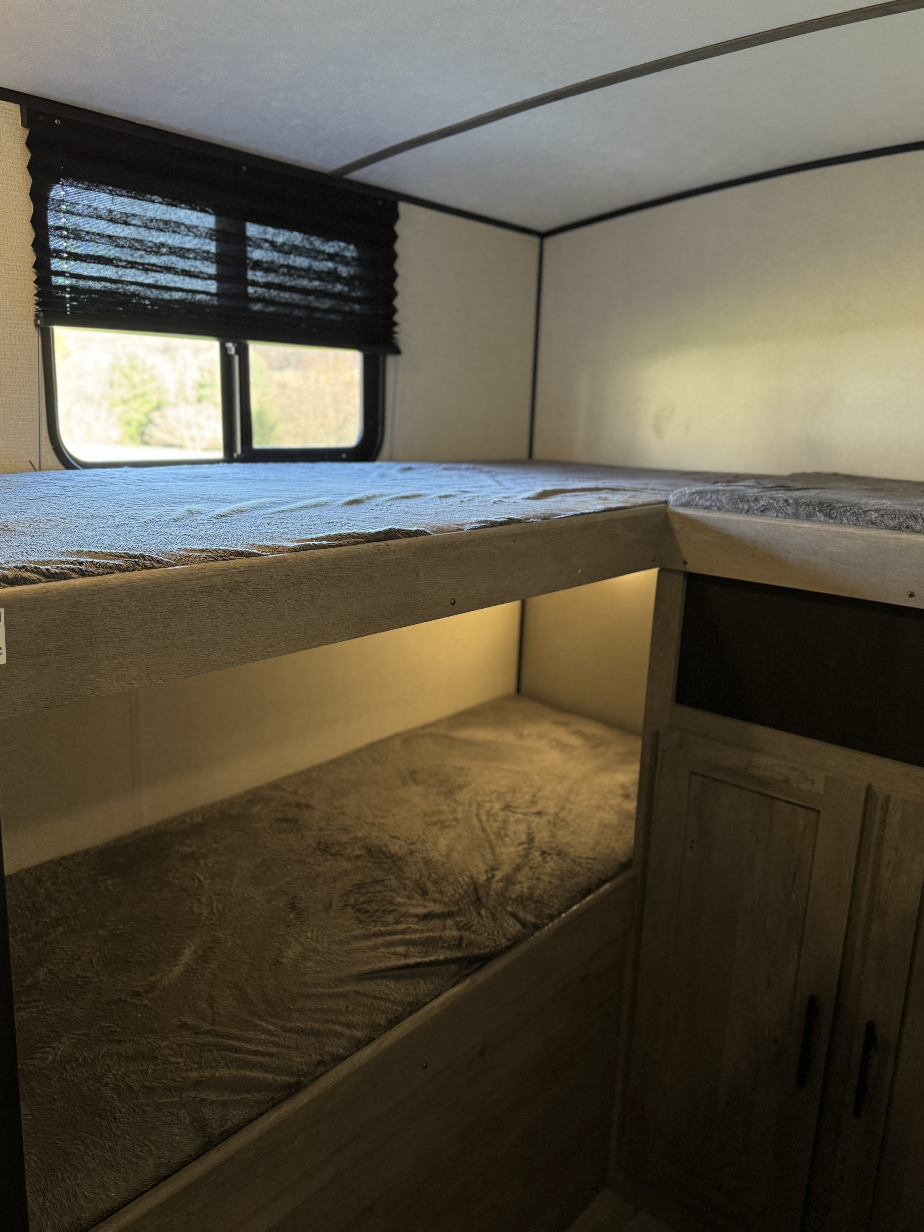 RV rental: Inside a camper, revealing cozy bunk beds with window views and a softly lit lower bunk.. Forest River Springdale 2021