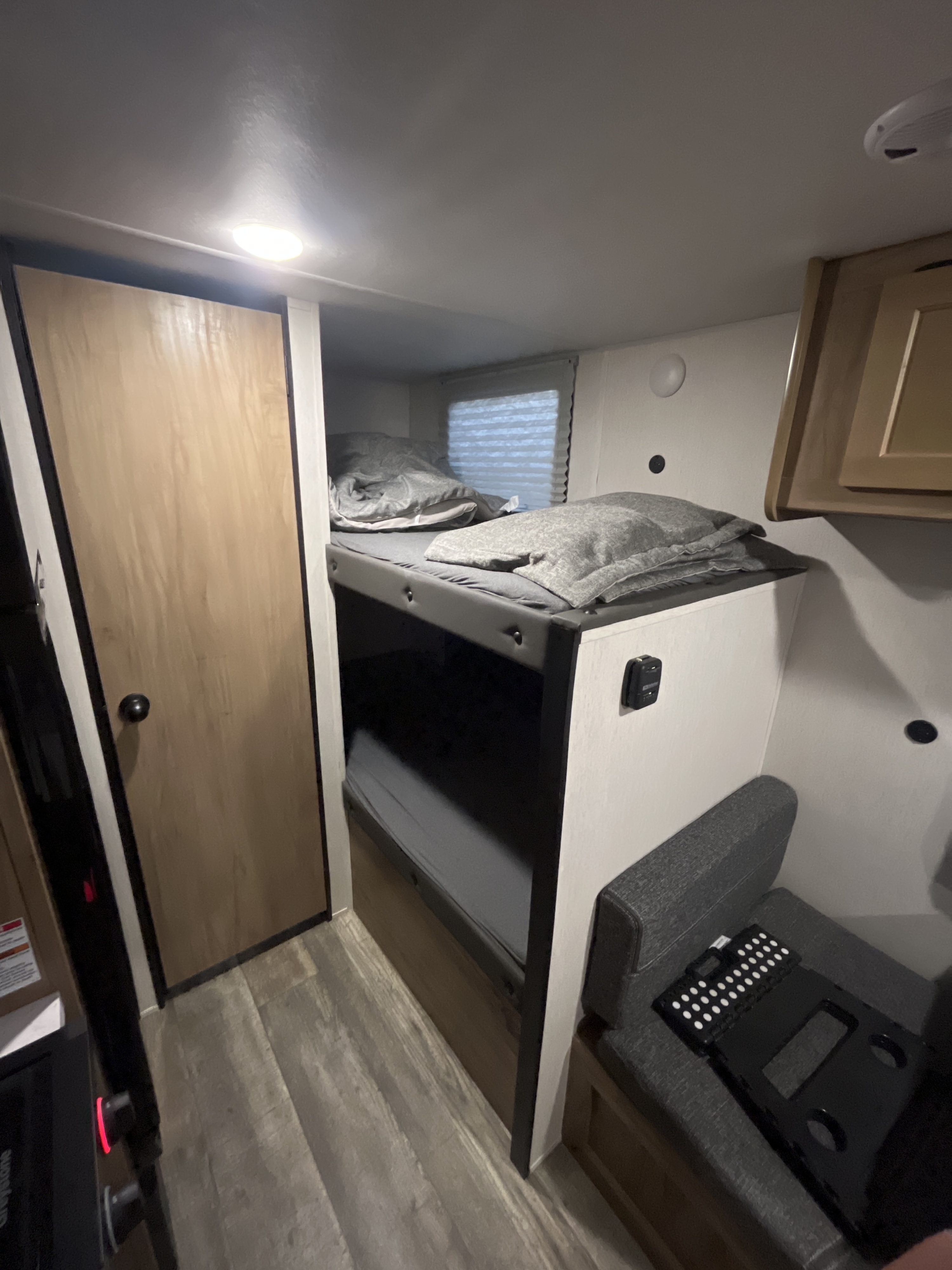 RV rental: Compact camper interior with two bunk beds, a wooden door, and a grey upholstered seating area.. Forest River Wolfpup16bhs 2024