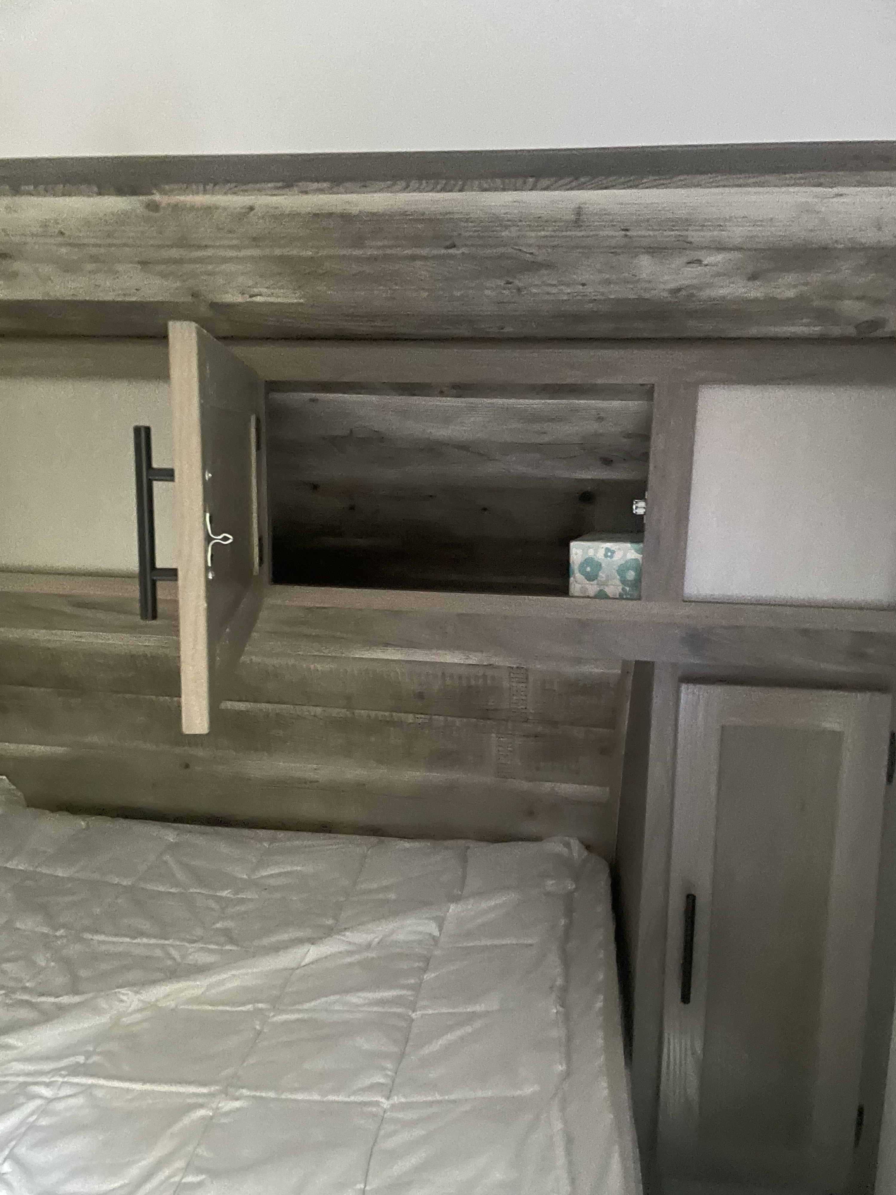 RV rental bedroom showcasing a bed and functional overhead storage cabinets, one open for compact living.. Gulf Stream Envision 2023