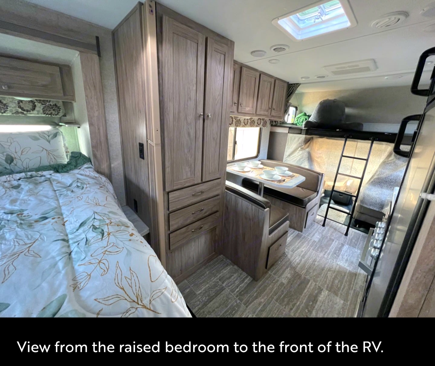 RV rental interior: Looking from the raised bedroom at the bed, wardrobe, dinette, and bunk beds with a ladder. Functional living space.. Forester LE 2021
