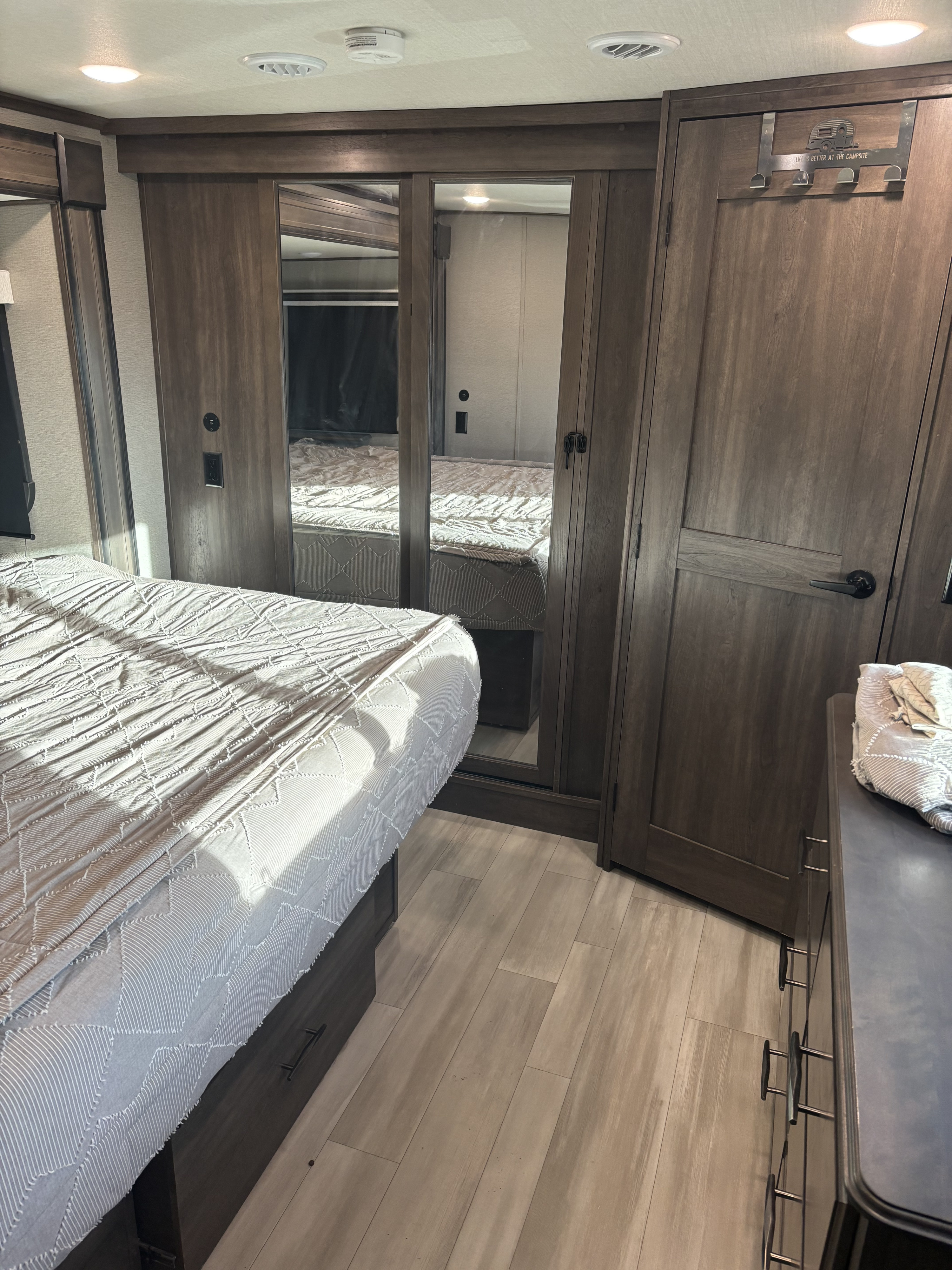 Spacious RV rental bedroom featuring a comfy bed, mirrored wardrobe, & modern interior for your camper getaway.. Grand Design Solitude 2022