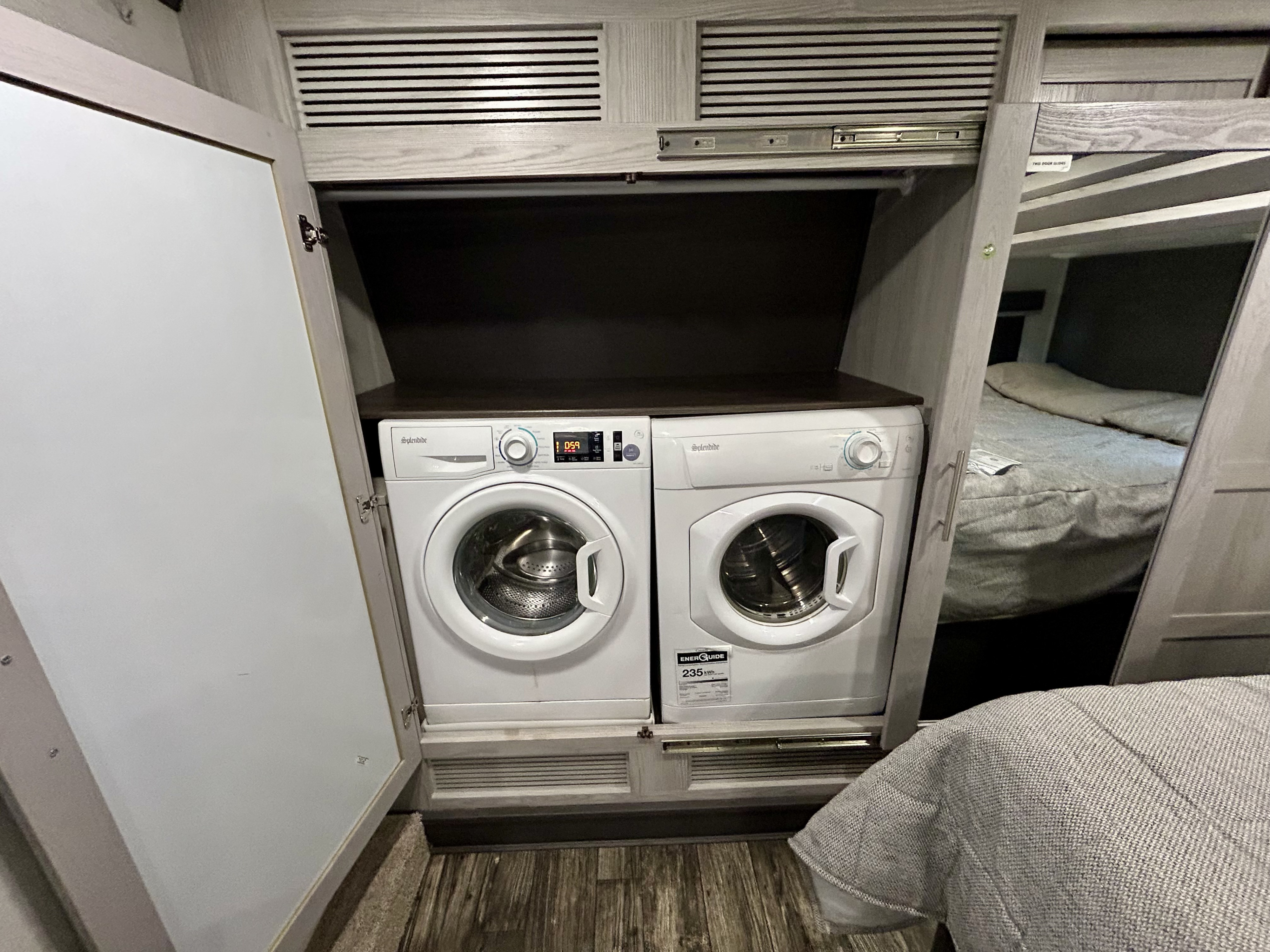 Side-by-side compact washer and dryer by Splendide in an RV rental. Efficient laundry solution next to bunk beds.. Keystone Fuzion 2022