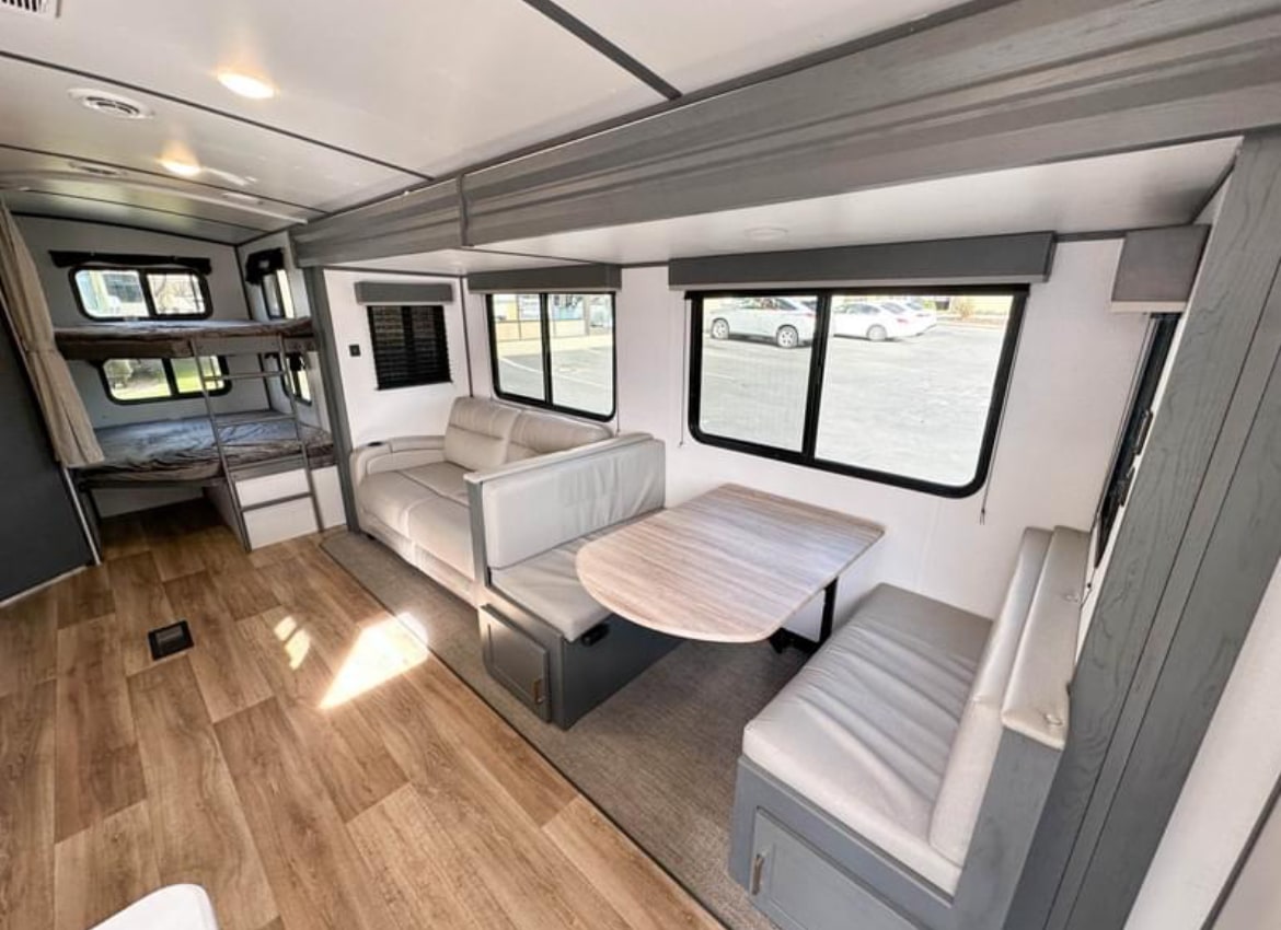 Explore this spacious RV rental interior: cozy bunk beds, a comfy sofa, and a versatile dinette area.. Keystone RV Bullet Ultra Lite 2023