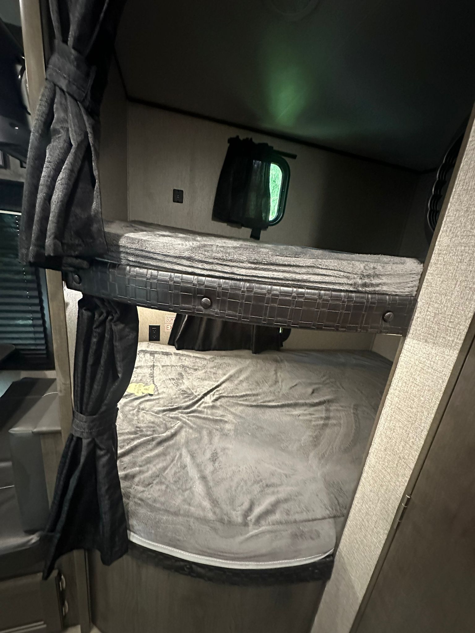 RV rental interior: two dark, cozy bunk beds with soft grey blankets & pulled-back privacy curtains, perfect for family sleeping.. Jayco Jay Flight 2021