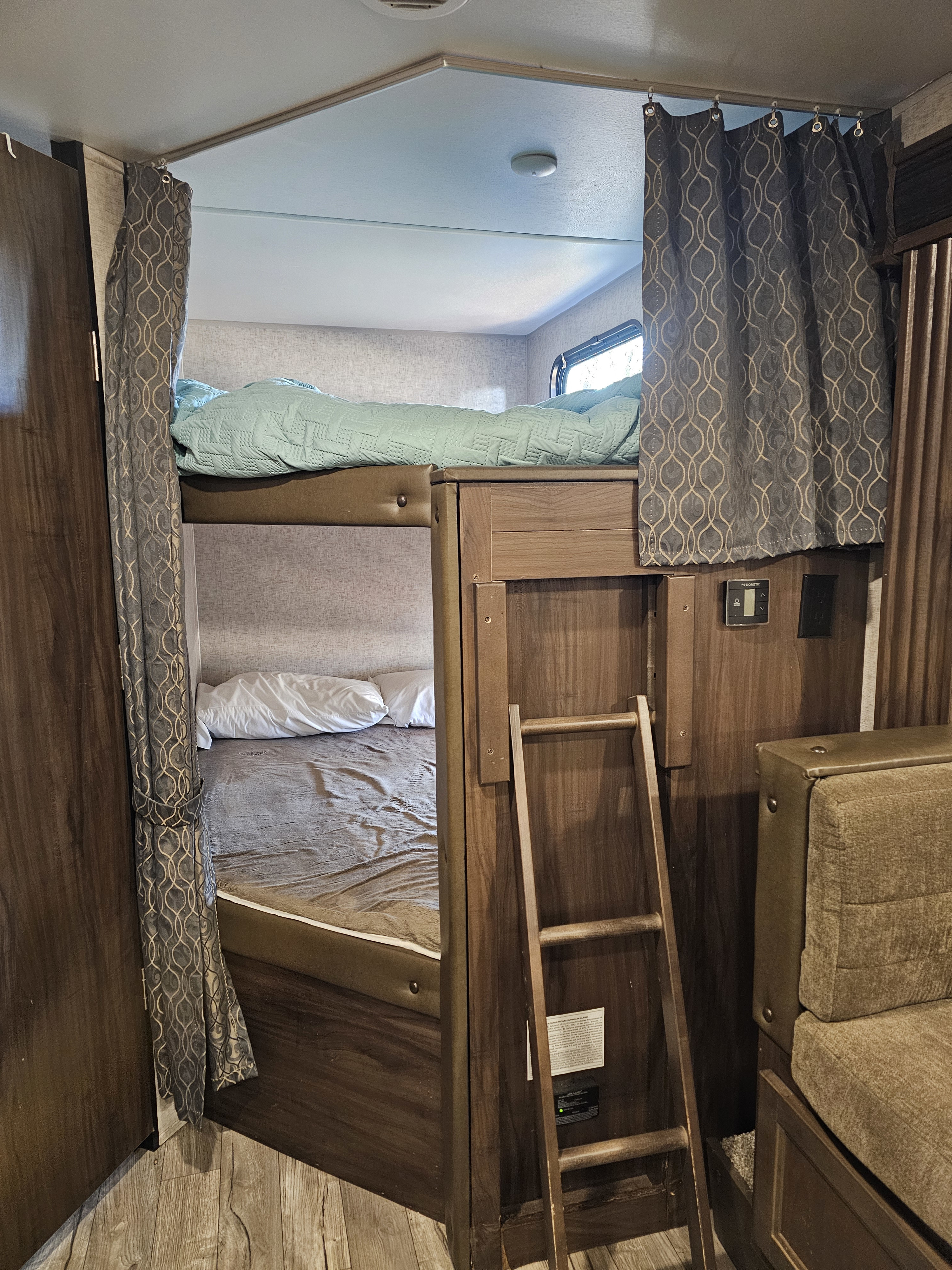 RV rental interior features bunk beds with privacy curtains, a ladder, and integrated controls, maximizing sleeping space.. Forest River Cherokee Grey Wolf 2019