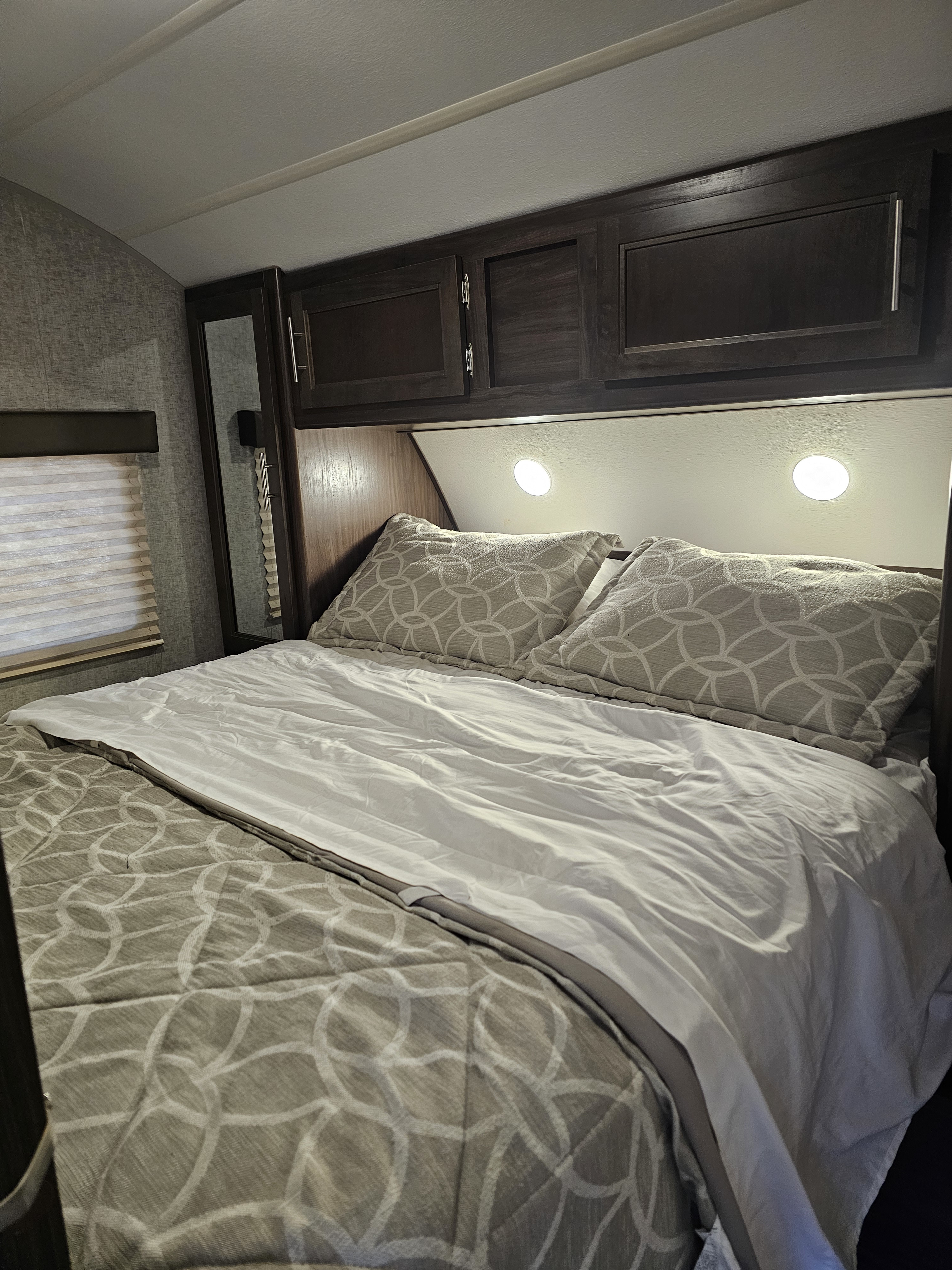 Cozy RV bedroom interior, perfect for your next rv rental adventure. Features a comfy bed, overhead storage, and reading lights.. Forest River Cherokee Grey Wolf 2019