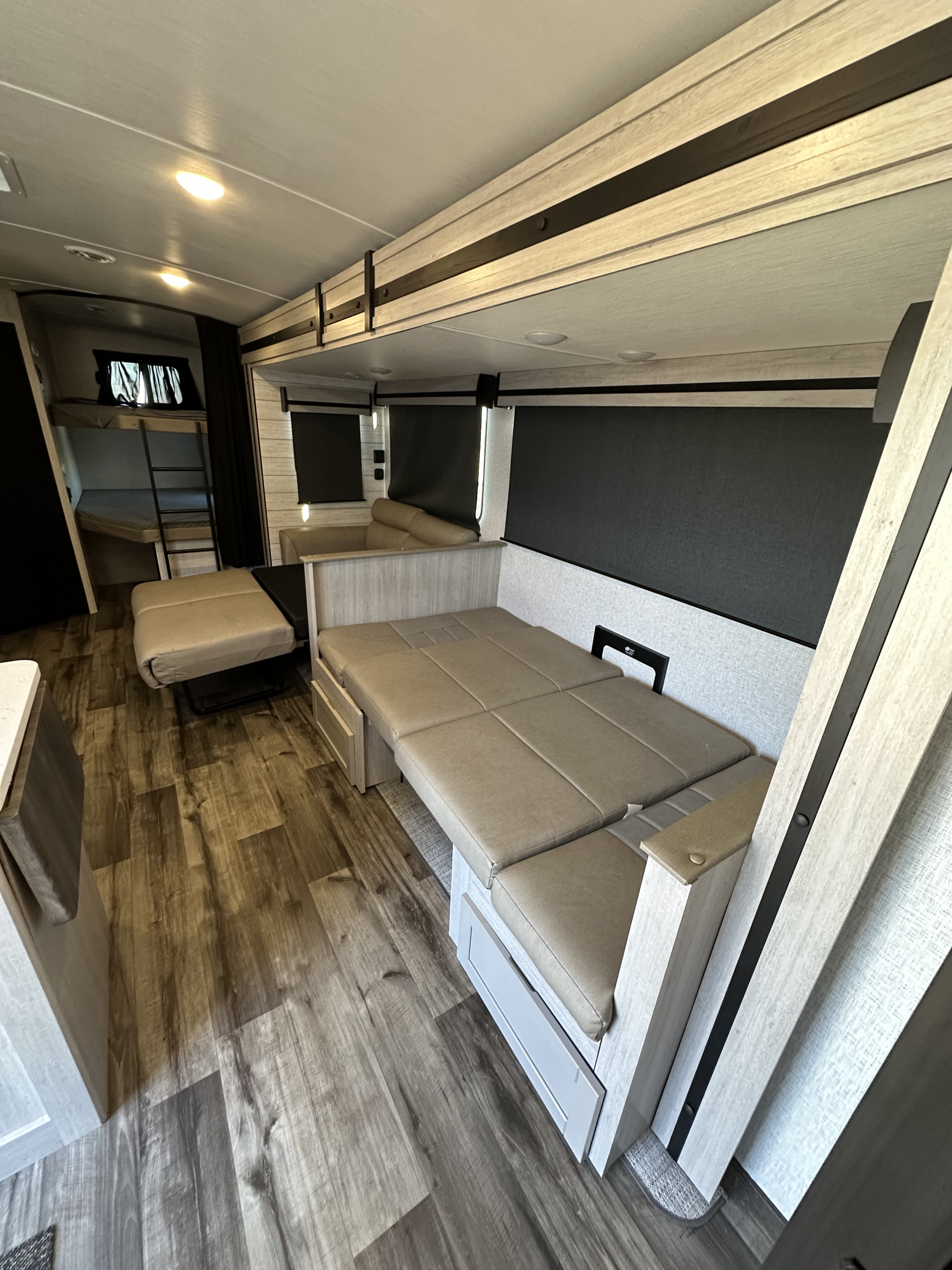 Spacious RV rental interior with bunk beds, a convertible dinette bed, and modern wood-look accents.. Keystone RV Sunset Trail 2024