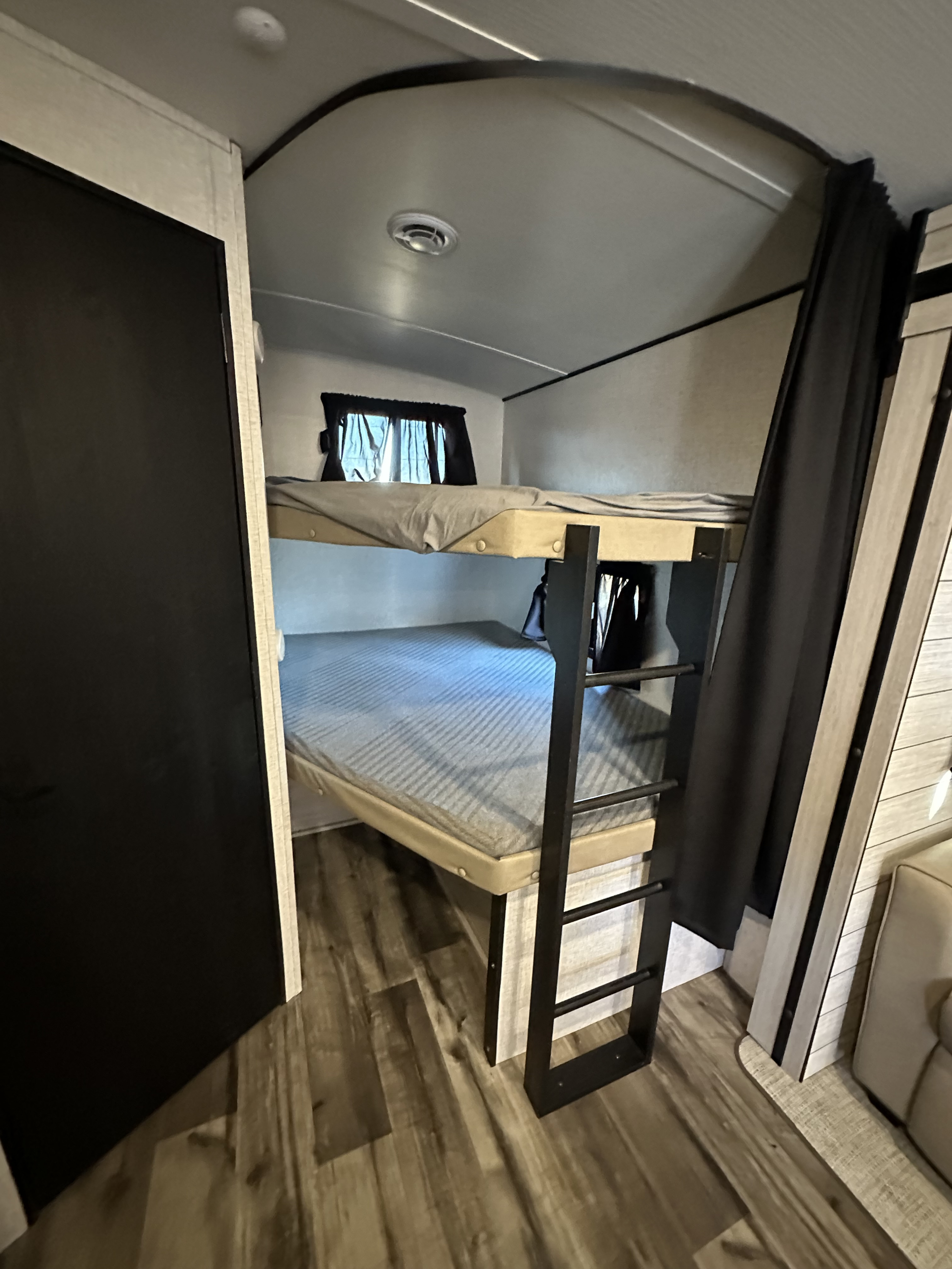 This RV rental offers a cozy bunk bed sleeping area with two beds, a ladder, and privacy curtains, perfect for family adventures.. Keystone RV Sunset Trail 2024