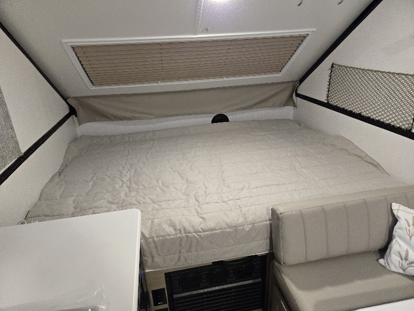 Inside a cozy A-frame RV rental: Features a large, comfortable bed, dinette, and bright interior for adventurers.. Forest River Rockwood Premier 2024
