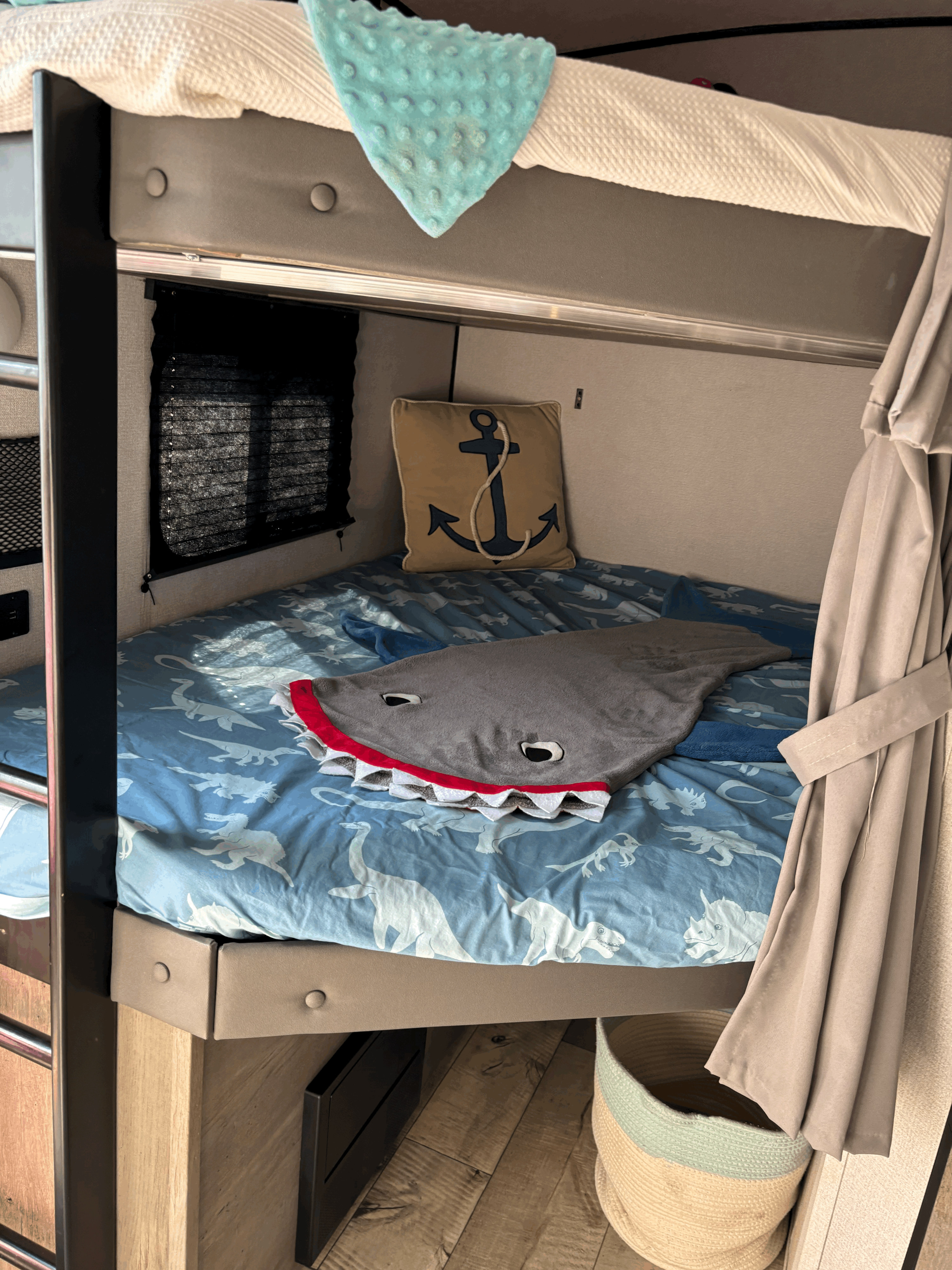 Cozy RV rental bunk bed for kids, featuring dinosaur sheets, a shark blanket, and an anchor pillow.. Keystone RV Springdale 2021