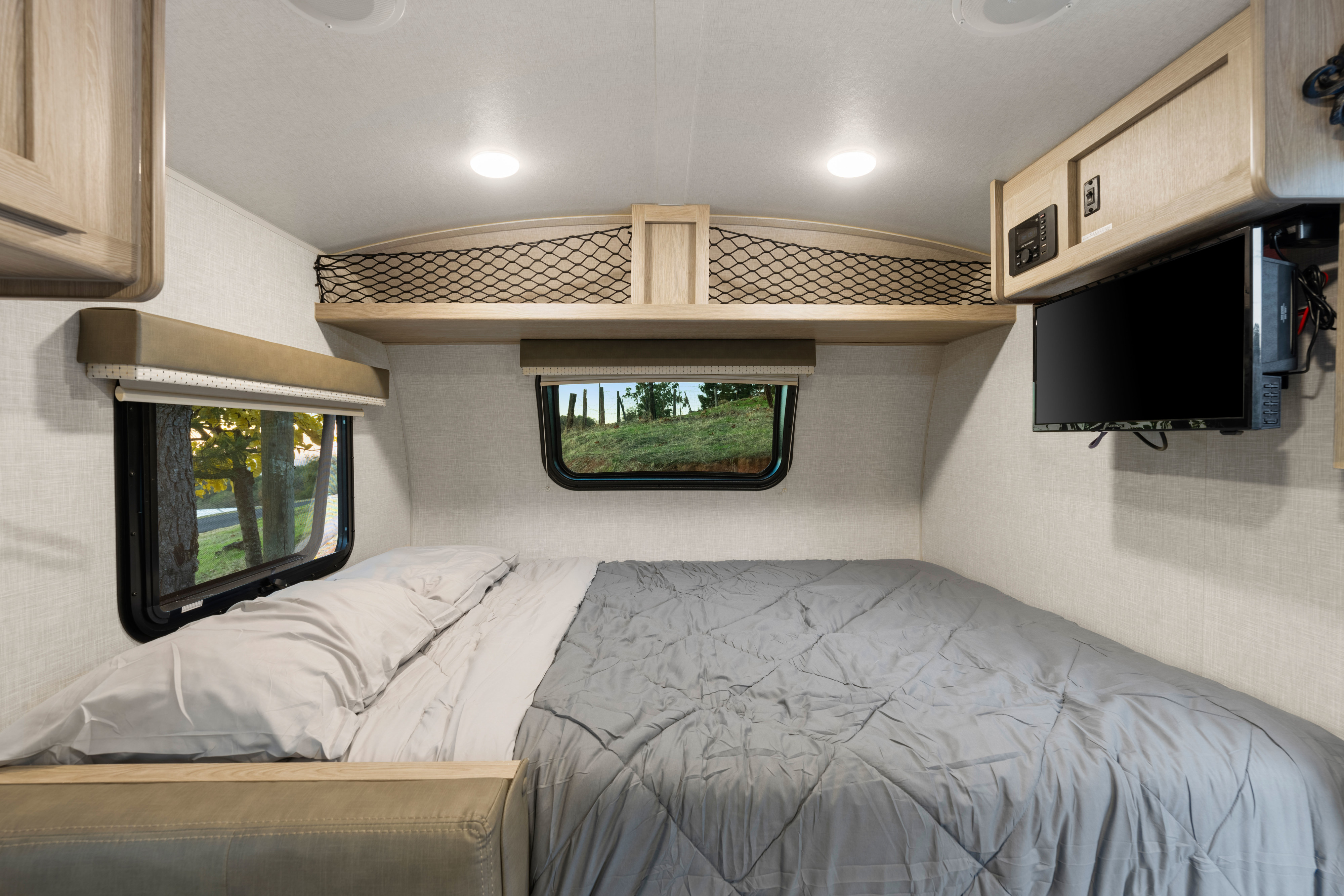 Cozy RV rental bedroom with a large bed, scenic windows, overhead storage, and a mounted TV.. Forest River Rockwood Geo Pro 2021