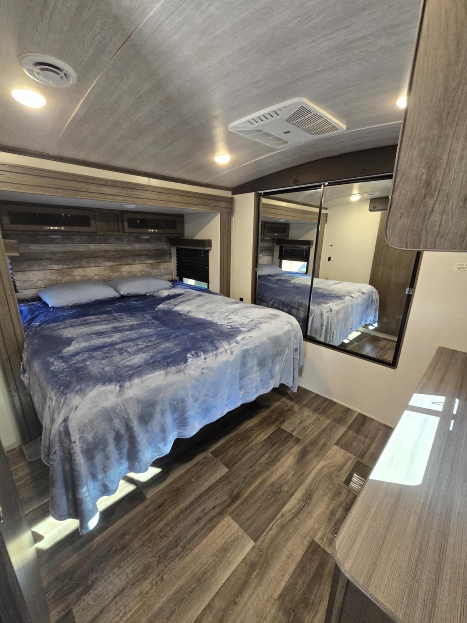 RV rental: A modern bedroom with a comfortable bed, overhead cabinets, and mirrored closet doors.. Keystone RV Cougar 2021
