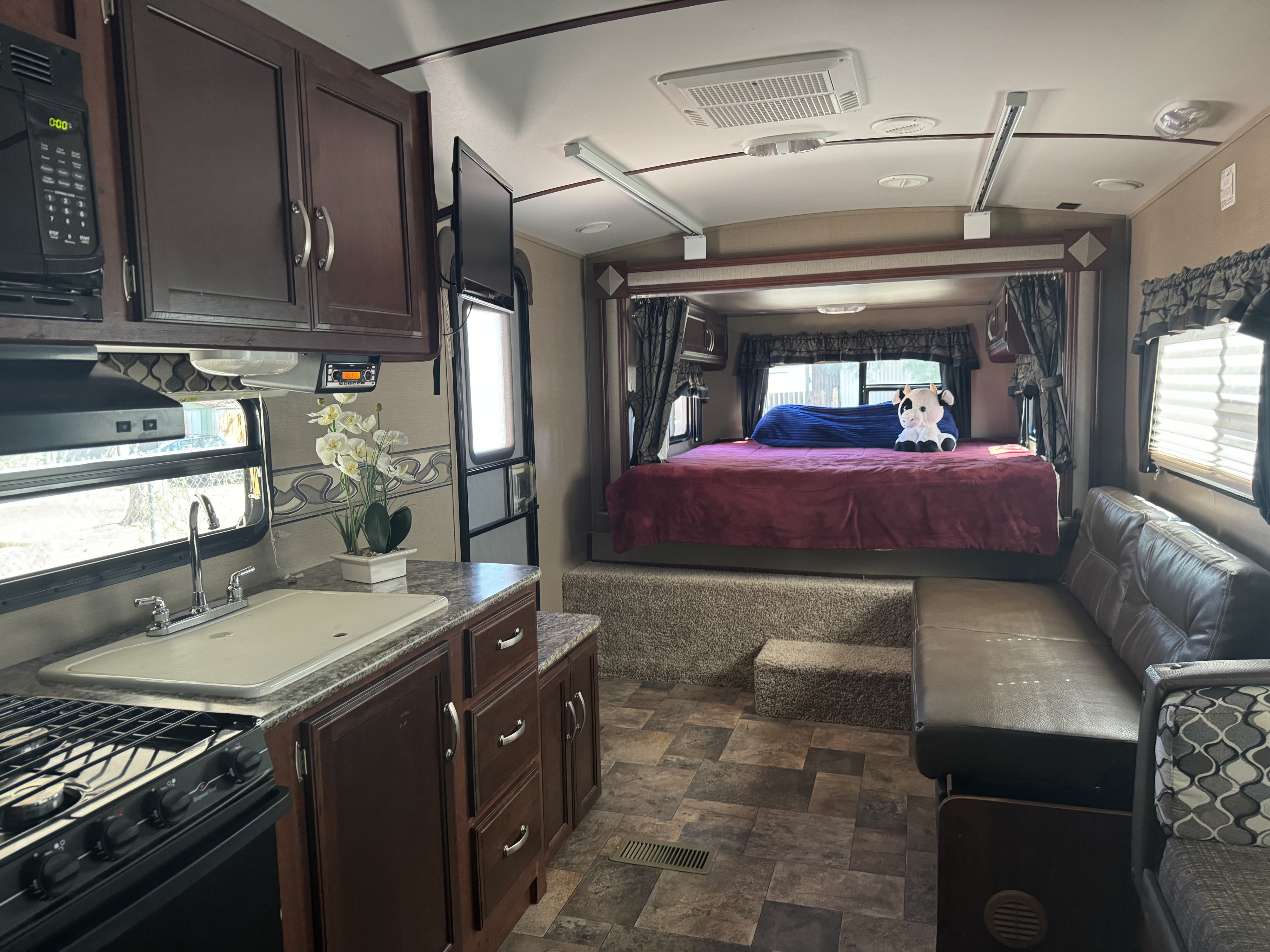 Spacious RV rental interior featuring a kitchen, living area, and comfortable raised bed, ideal for travel and camping.. Keystone RV Outback Terrain 2014