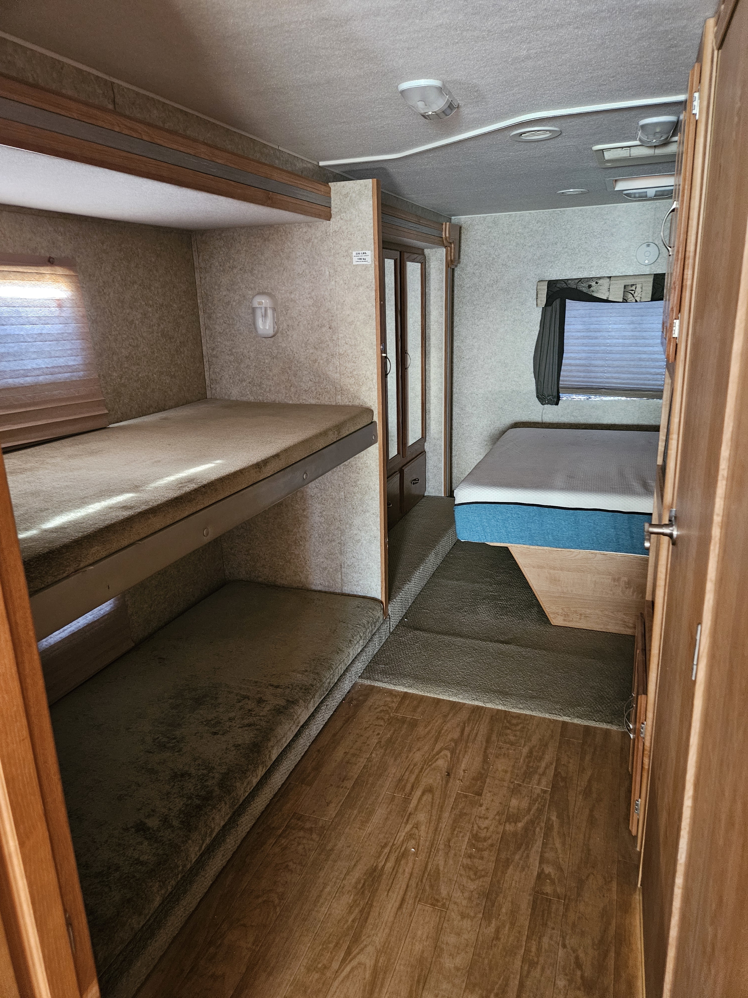 RV rental interior with comfortable bunk beds on the left and a raised main bed on the right.. Coachmen Mirada 2007