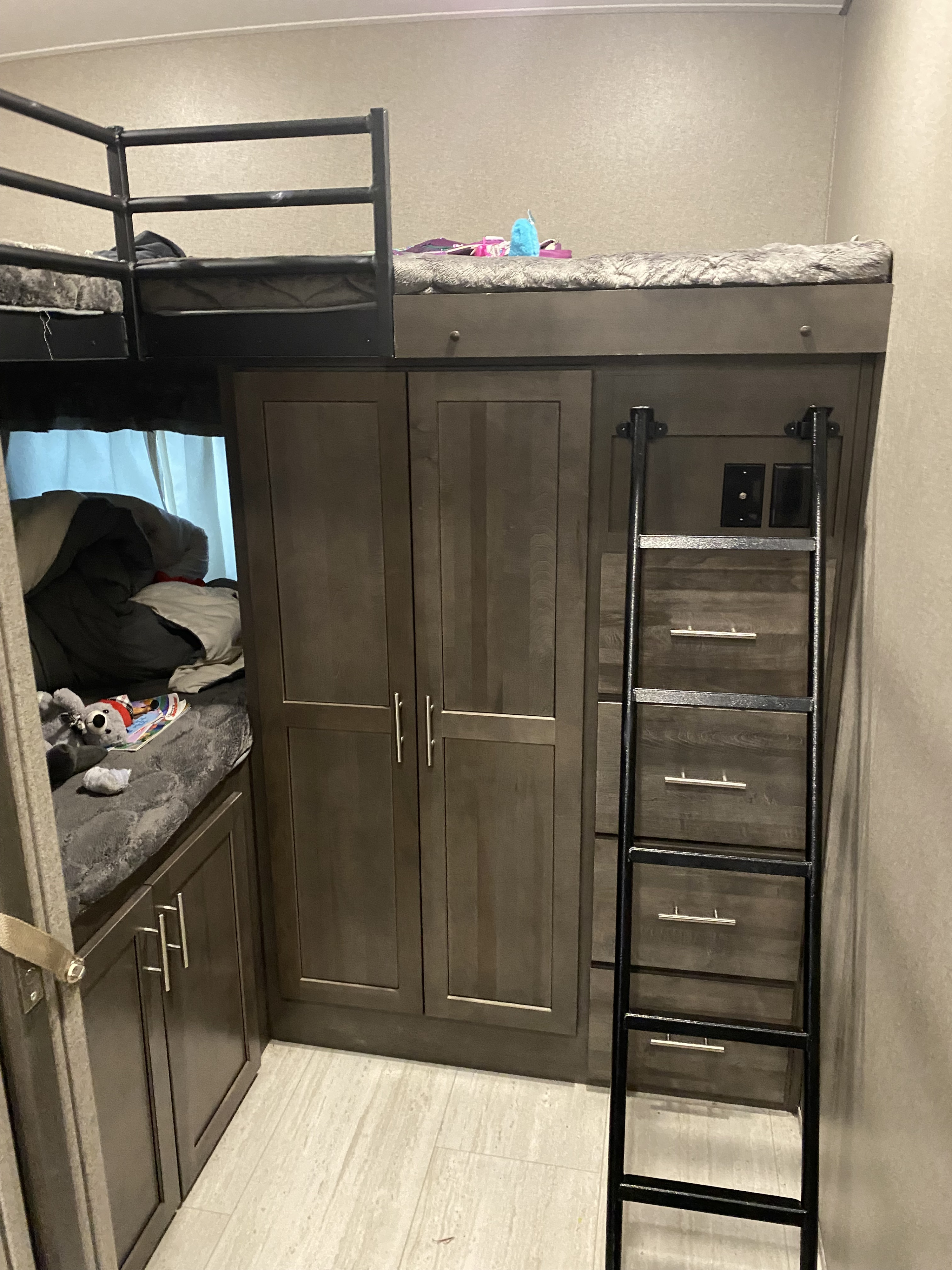Compact RV rental interior featuring bunk beds, a ladder, and built-in storage cabinets and drawers, ideal for family trips.. Forest River Flagstaff Super Lite 2021