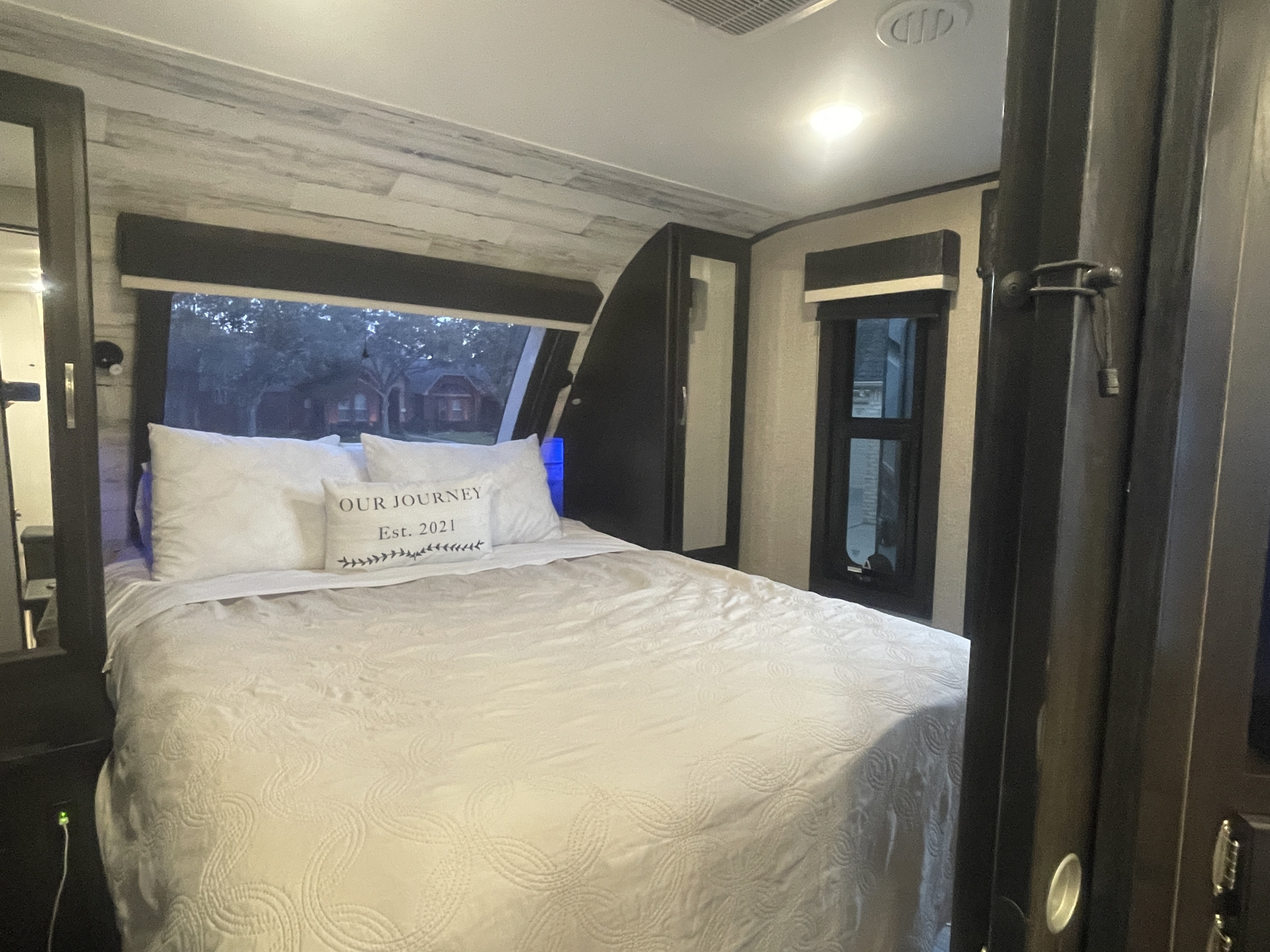 Cozy RV rental bedroom with a comfortable bed, white bedding, and wood-look walls, offering a serene escape.. Jayco White Hawk 2021