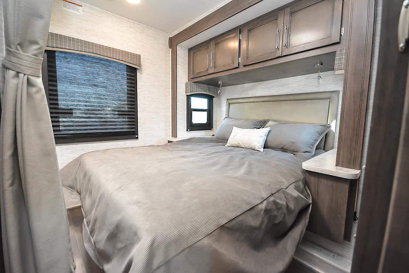 Comfortable RV rental bedroom with a large bed, overhead storage cabinets, and bright windows on textured walls.. Jayco Redhawk SE 2024