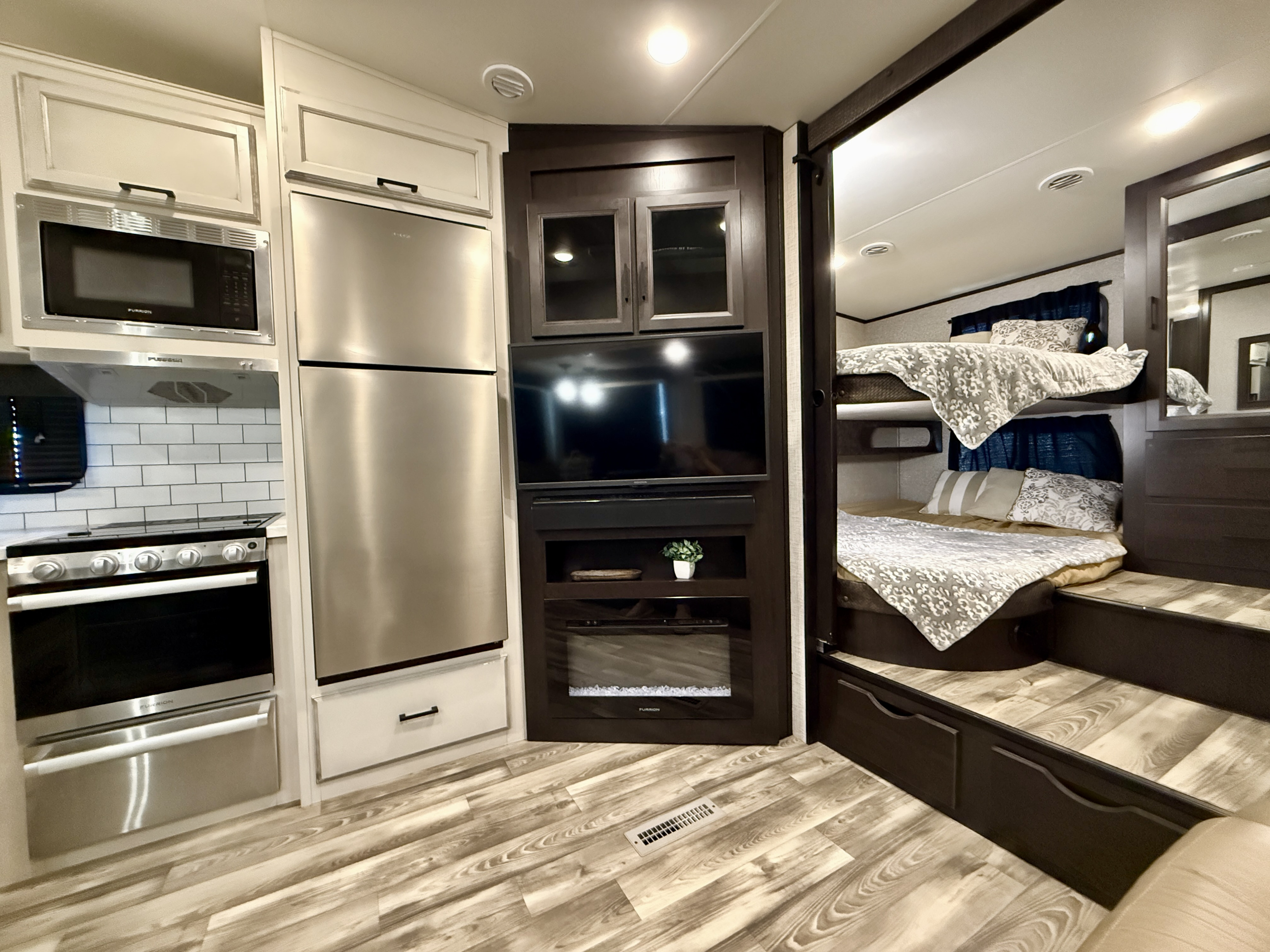 Spacious RV rental interior: Features a modern kitchen, large refrigerator, entertainment center with TV & fireplace, plus cozy bunk beds.. Jayco Jayco 2022