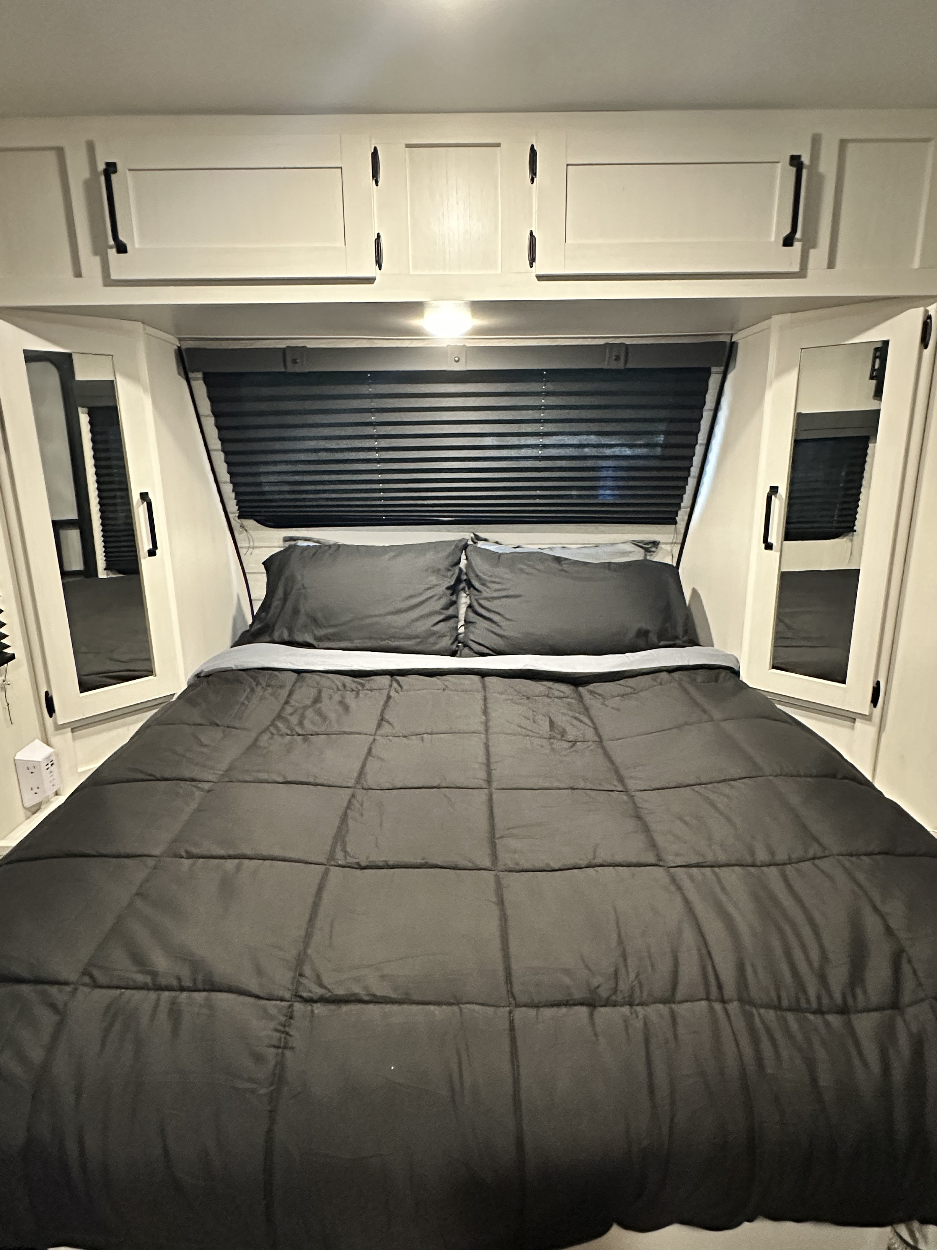 Inside an rv rental, a compact bedroom with a comfy bed, overhead storage, and privacy blinds.. Forest River Palomino Puma 2024