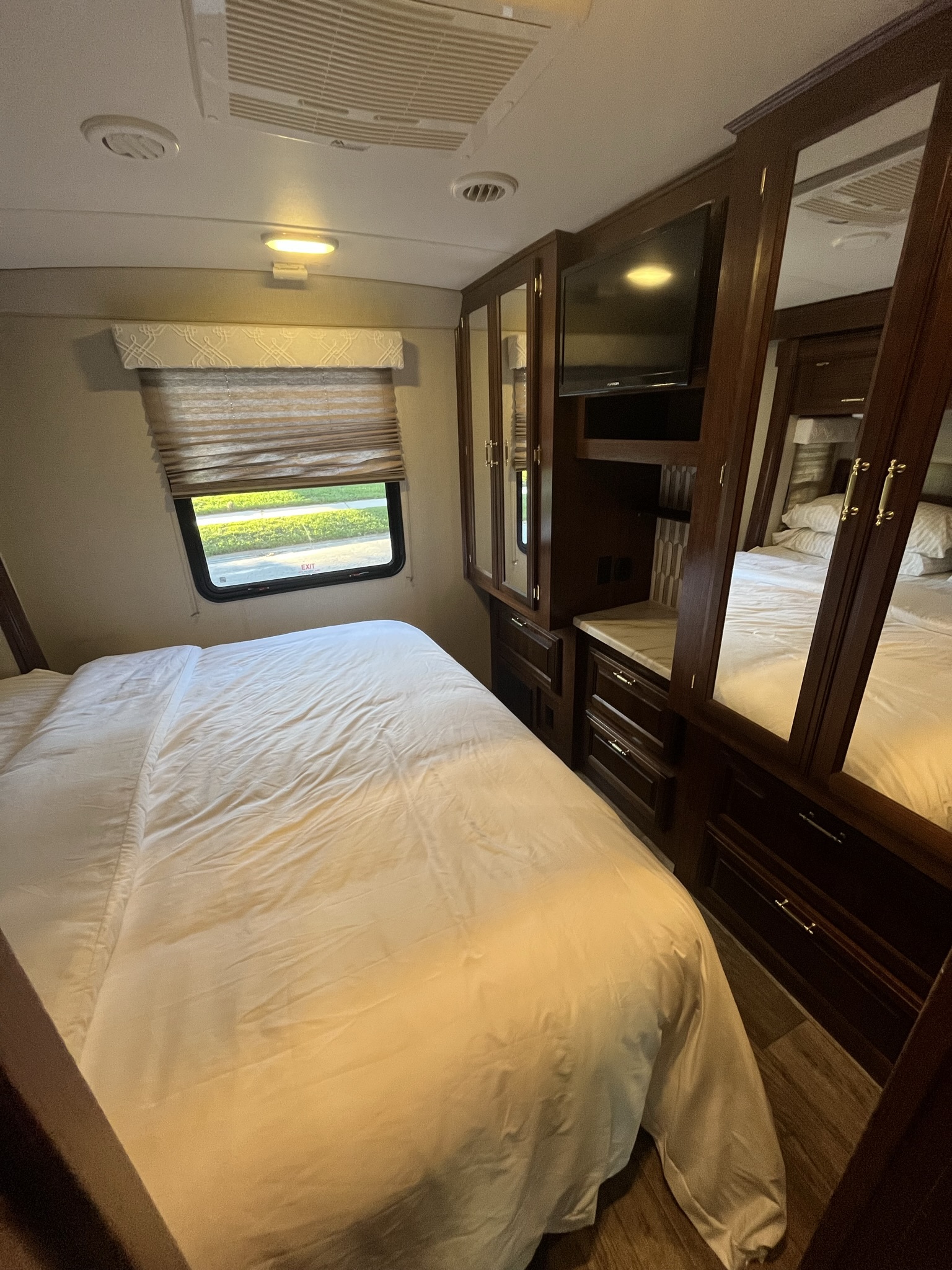 RV rental bedroom features a comfy white bed, window, and wood cabinets with a TV.. FR3 FR3 Motorhome 2018