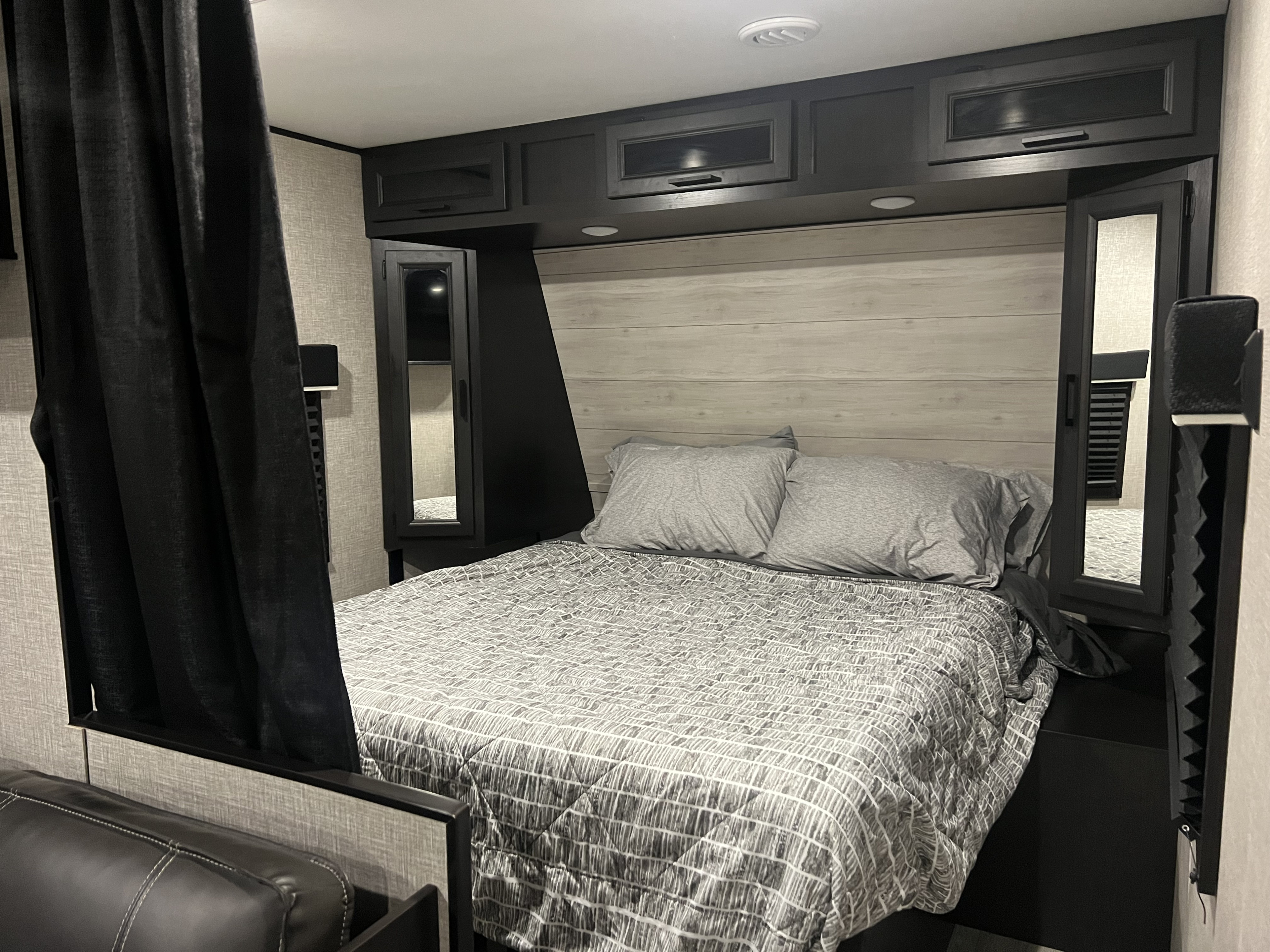 Cozy RV rental bedroom with modern black cabinetry, light wood-look headboard, and patterned bedding. Perfect for a comfortable stay.. Jayco Jay Flight 2022