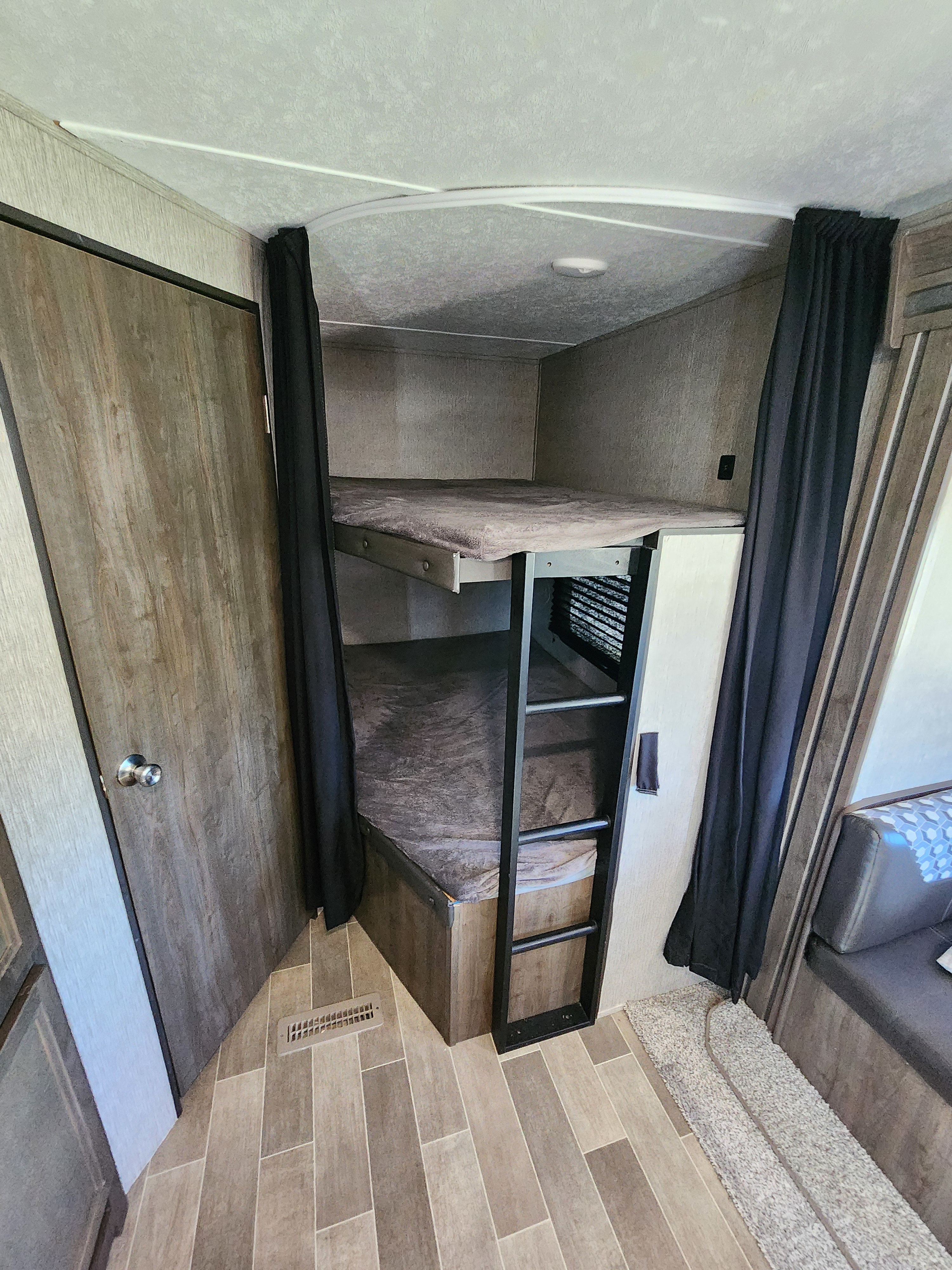 Cozy bunk beds in an rv rental, perfect for family adventures. Features a ladder and comfortable sleeping areas.. Dutchmen Coleman Lantern 2019