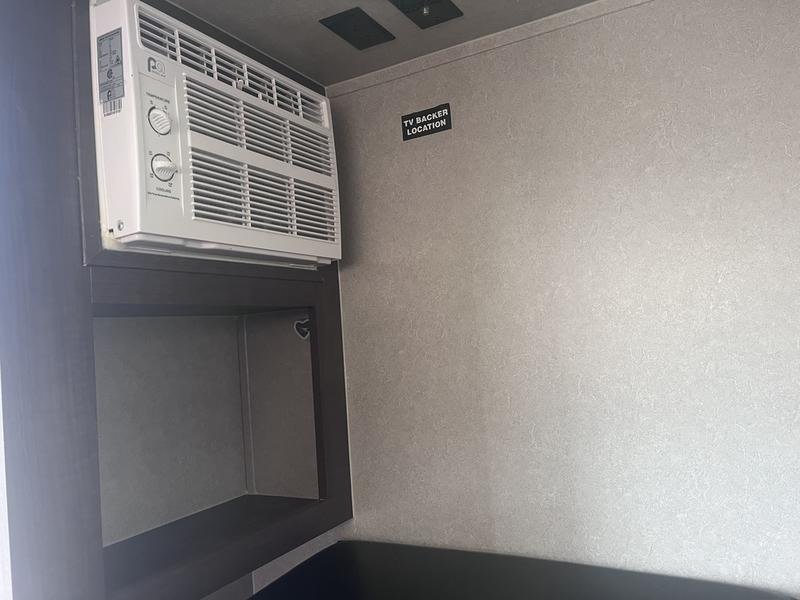 This RV rental interior features an AC unit, built-in storage shelf, and a clearly labeled "TV Backer Location" for mounting.. Sunset Park RV SunRay 2021