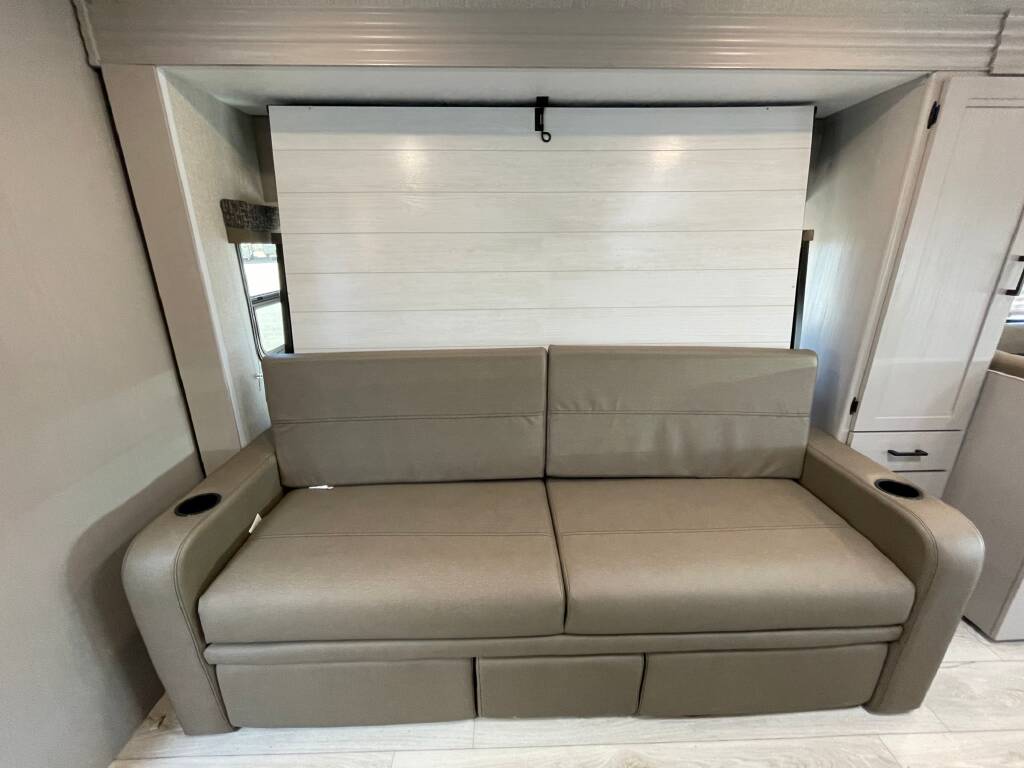 RV rental: Beige convertible sofa with armrest cup holders, located in a light-paneled interior, perfect for relaxing.. Forest River Coachmen Freelander 2026