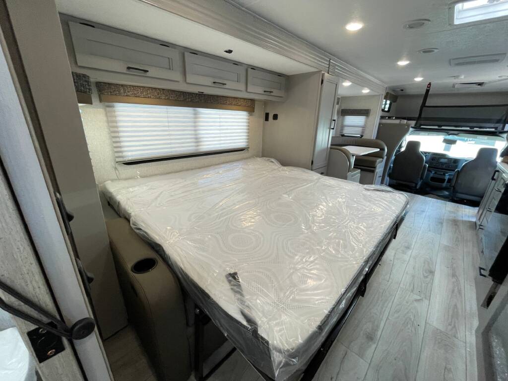 Inside this rv rental: new bed with plastic cover, cozy dinette, and front cockpit. Ready for your next adventure!. Forest River Coachmen Freelander 2026