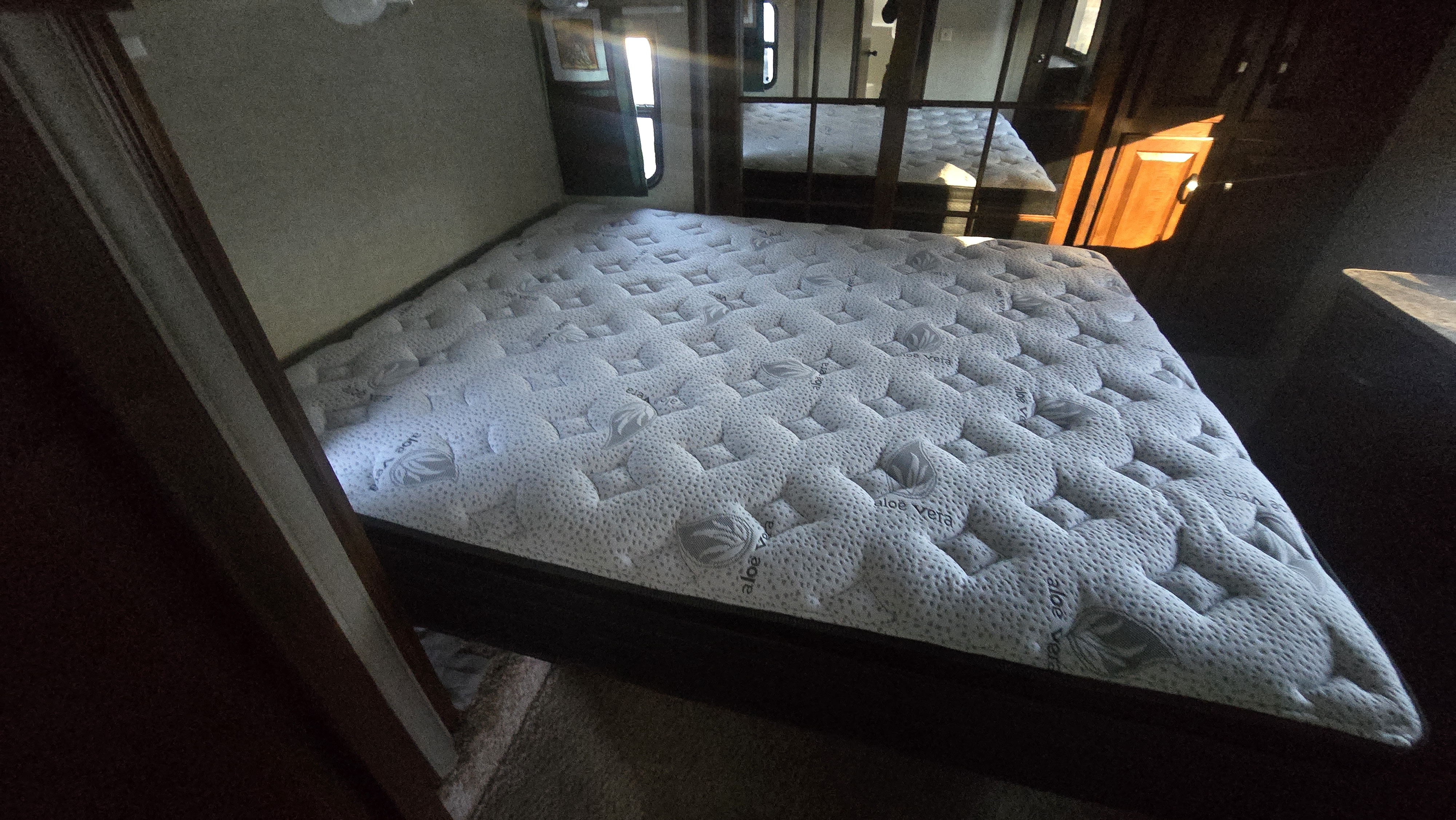 Brightly lit RV rental bedroom showing a clean, quilted Aloe Vera mattress and mirrored doors.. Keystone Laredo 2013