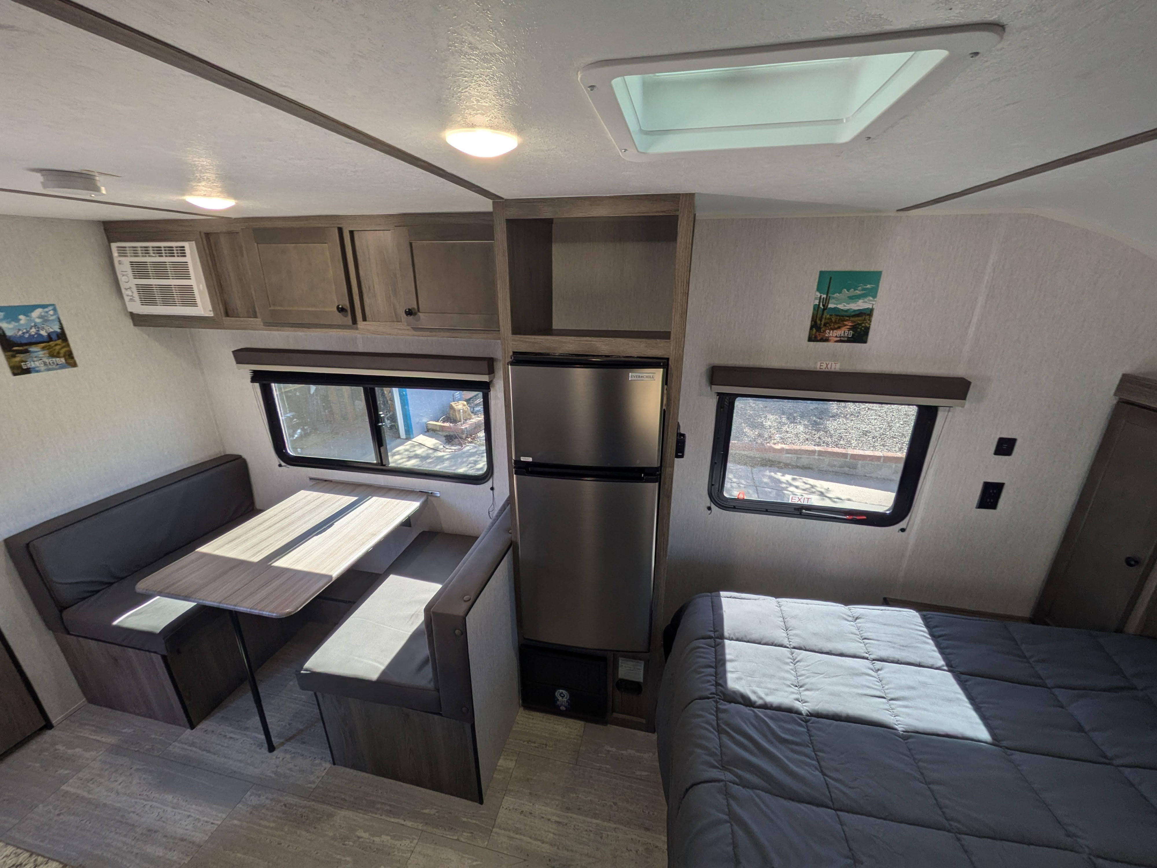Spacious RV rental interior featuring a dinette, kitchen with fridge, and a cozy bed area, perfect for travel.. Sunset Park & Rv Inc. 19rb 2025