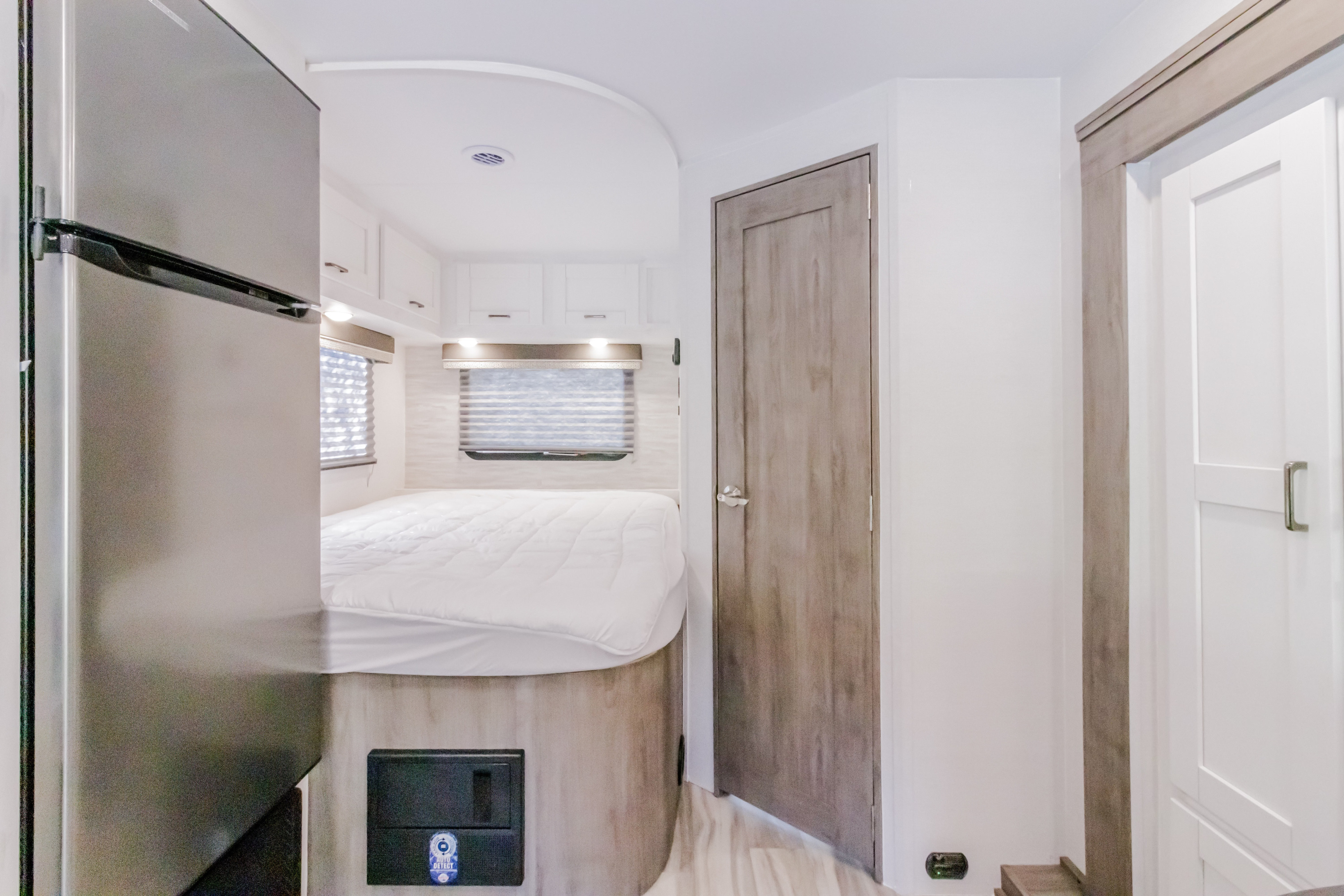 RV rental interior featuring a bed with white bedding, overhead cabinets, windows, and a full-size refrigerator.. GULFSTREAM CONQUEST 6238 2025