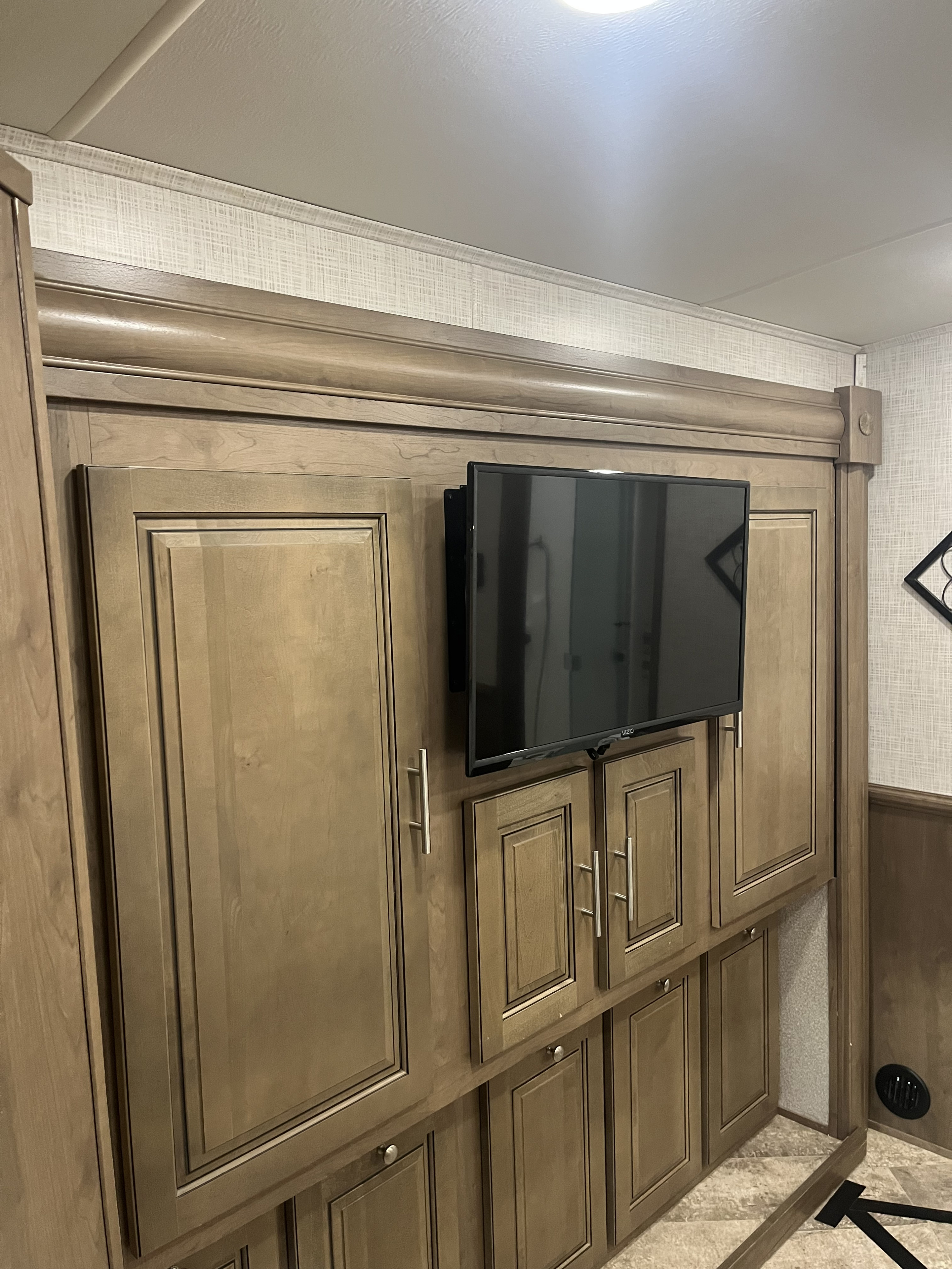 RV rental bedroom: light wood cabinetry, a wall-mounted Vizio TV, and textured walls provide storage and entertainment.. Forest River Georgetown 2019