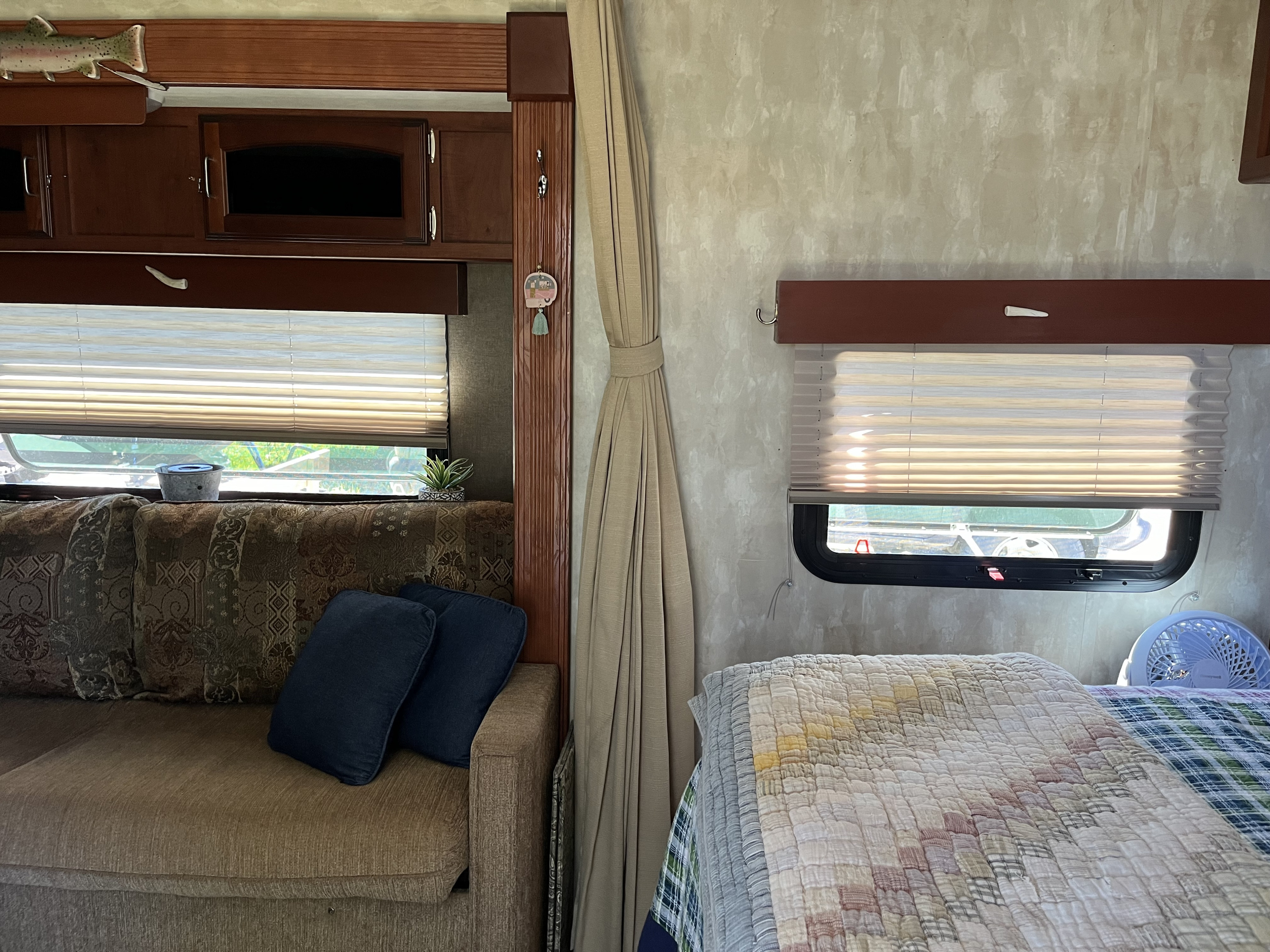 Cozy RV rental interior: features a comfortable sofa, bed with quilt, and windows with blinds, ideal for travel.. Winnebago Minnie Winnie 2014