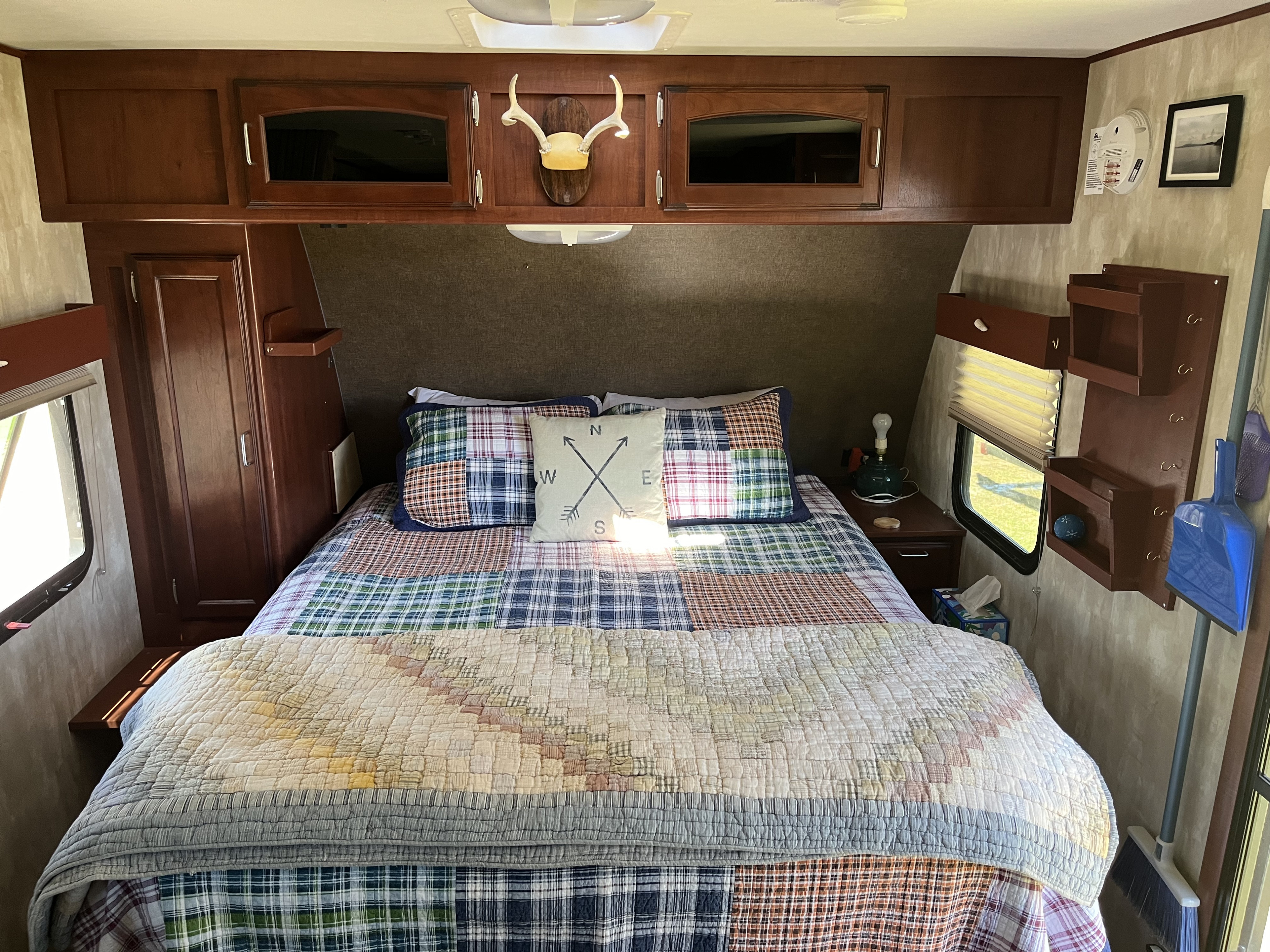 Cozy RV rental bedroom featuring a patterned bed, wood cabinets, and homey decor for comfortable travel.. Winnebago Minnie Winnie 2014