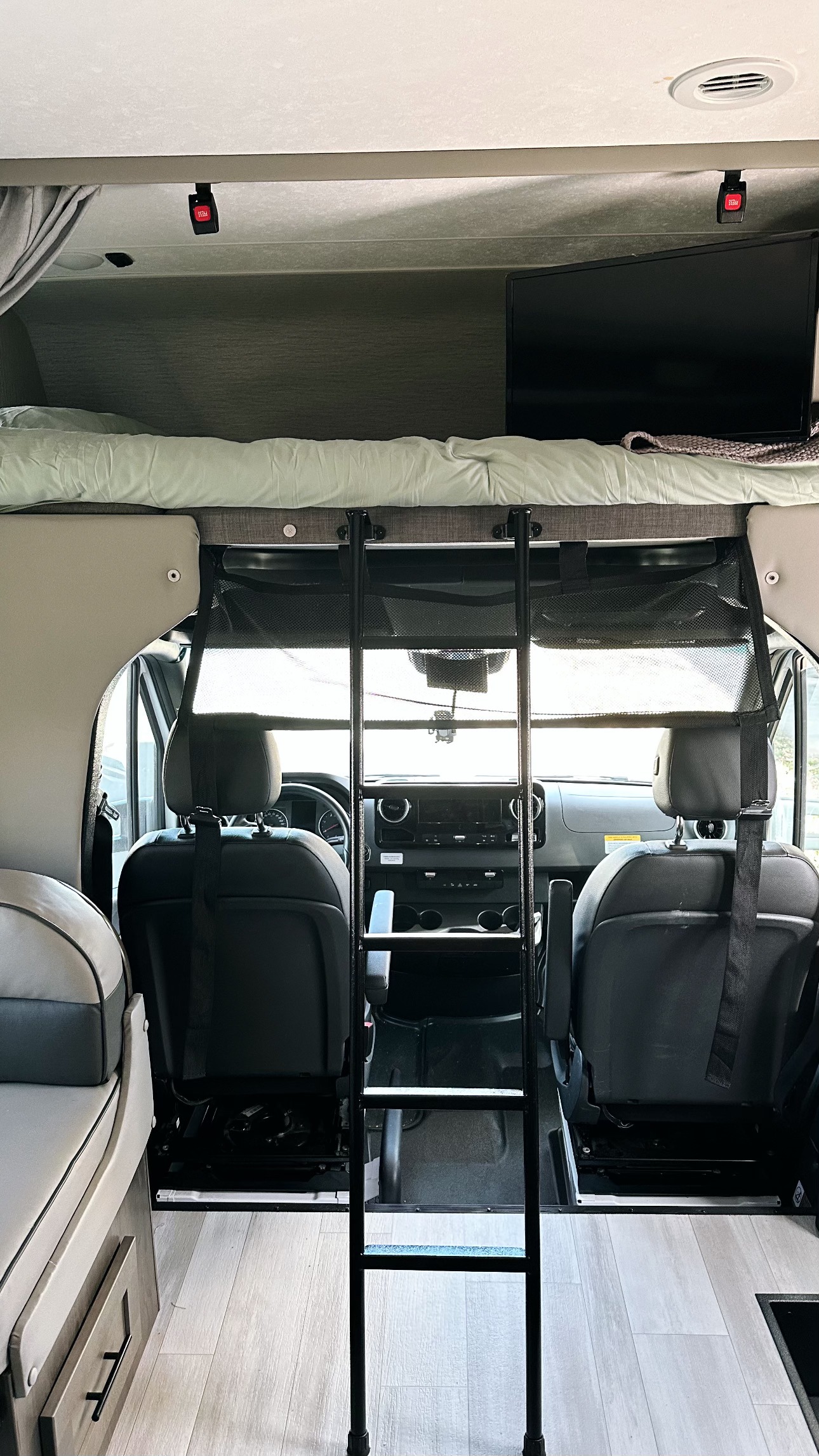 **RV rental** interior features a comfortable overhead bunk with ladder, a TV, and the driver's cockpit.. Mercedes Coachman Prism 2023