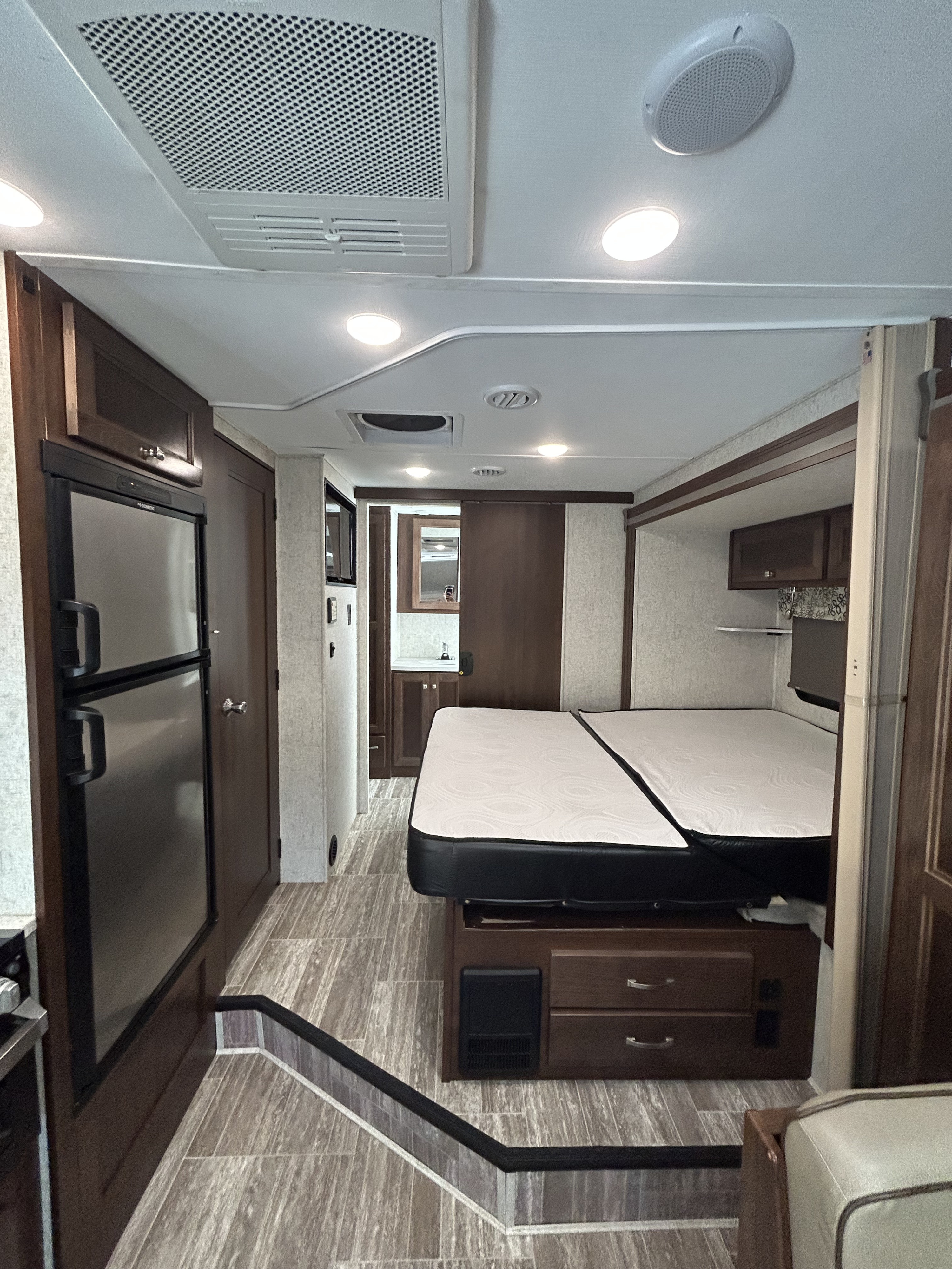 Modern RV rental interior: featuring a spacious bed, functional kitchen, and bright living area with steps.. Forester 2441DS 2019