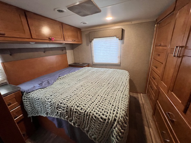 Comfortable RV rental bedroom featuring a bed, overhead cabinets, and built-in storage. Ideal for travel.. Winnebago Mini Winnie 2019