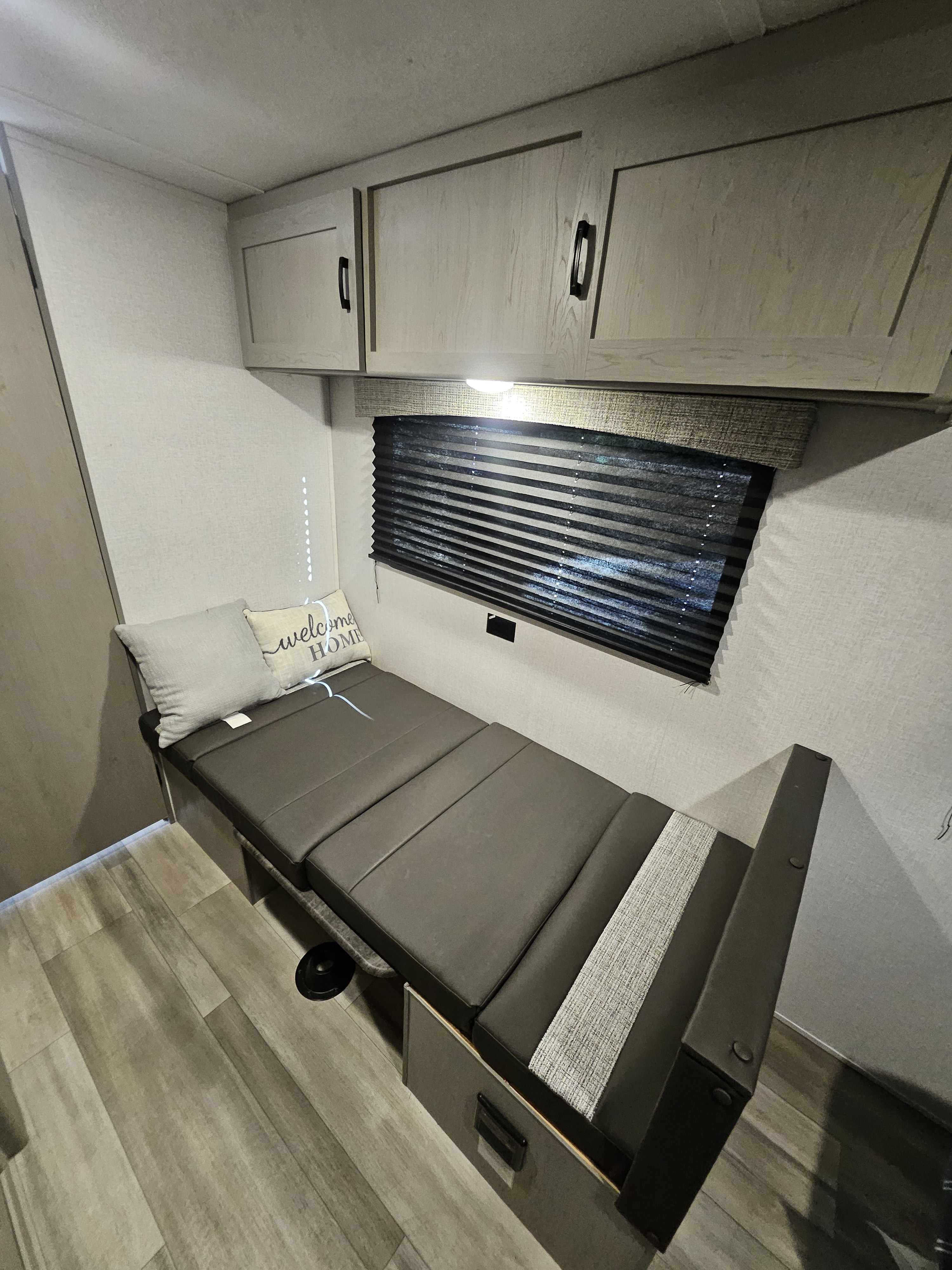 This RV rental features a convertible bench that becomes a bed, light wood overhead cabinets, and a window with blinds.. Forest River Clipper 17CFQ 2023